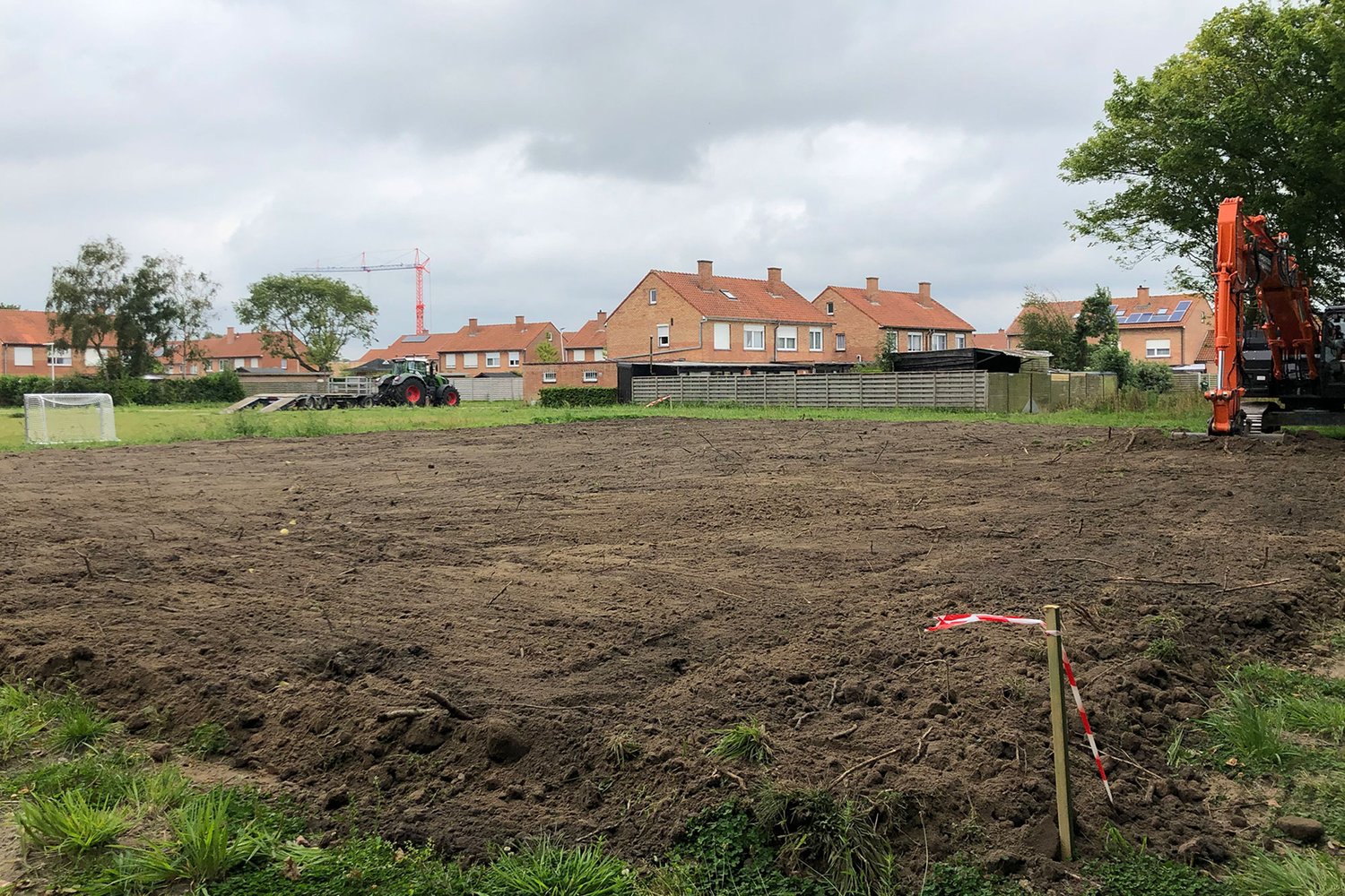 a dirt field with. ahouse in the background