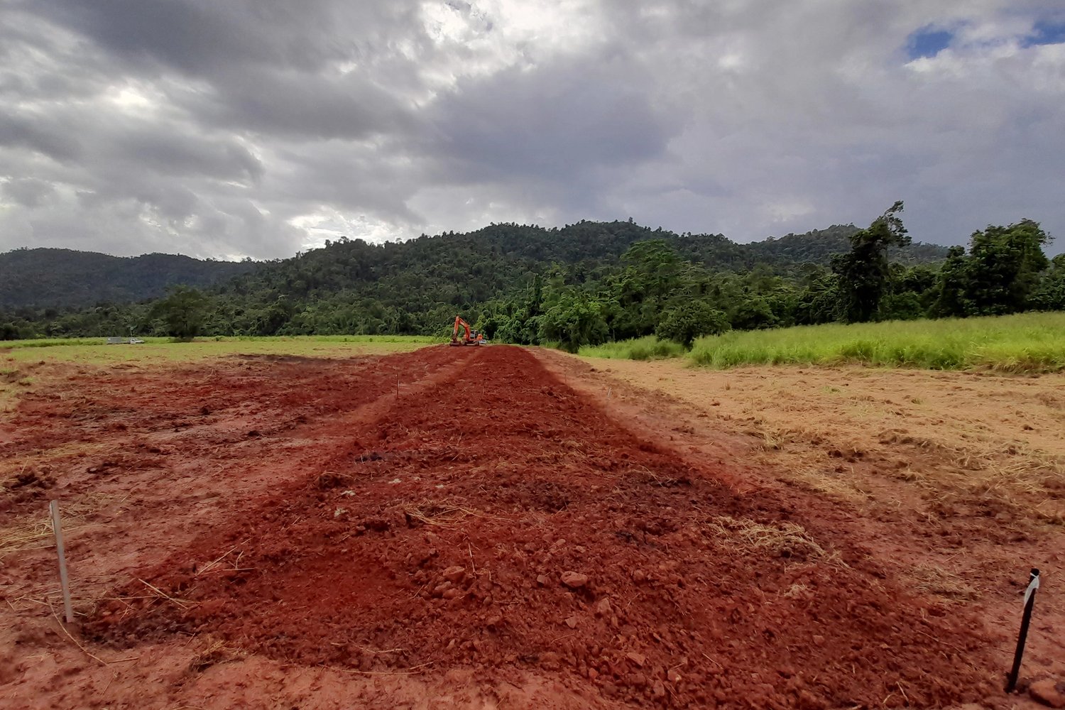 a dirt field and green mountains