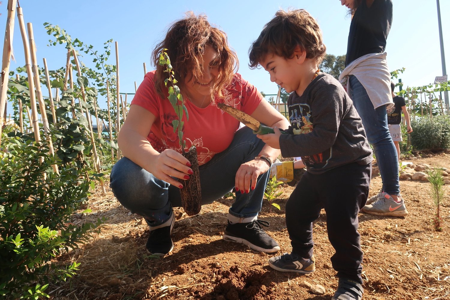 a woman and young boy kneel in a field