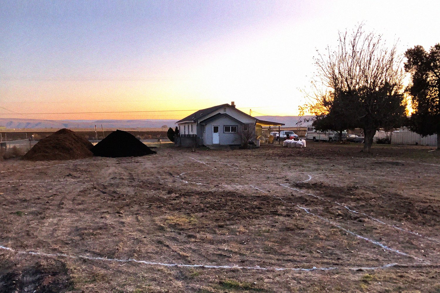 white lines drawn in the dirt with a house in the background