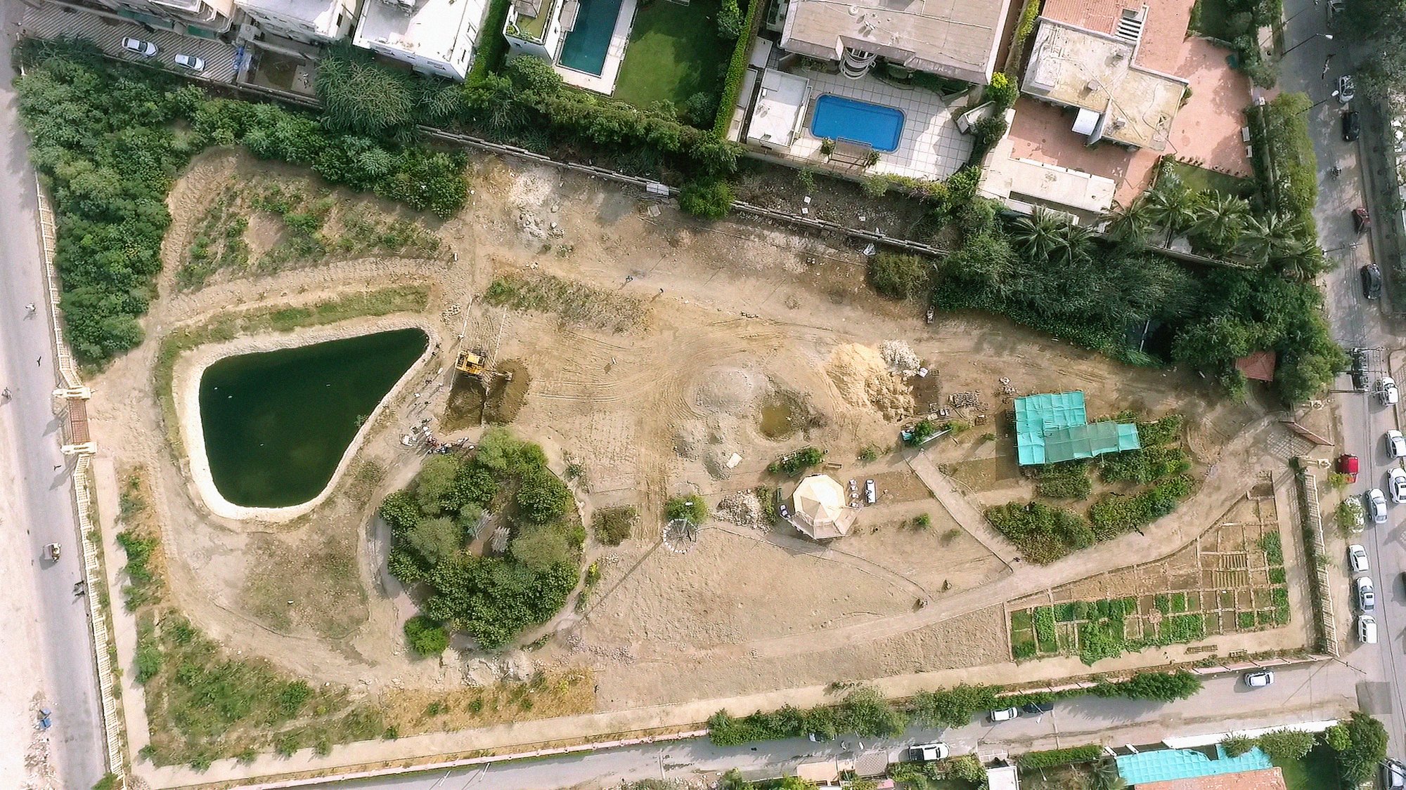 a dirt field with a pond as seen from above