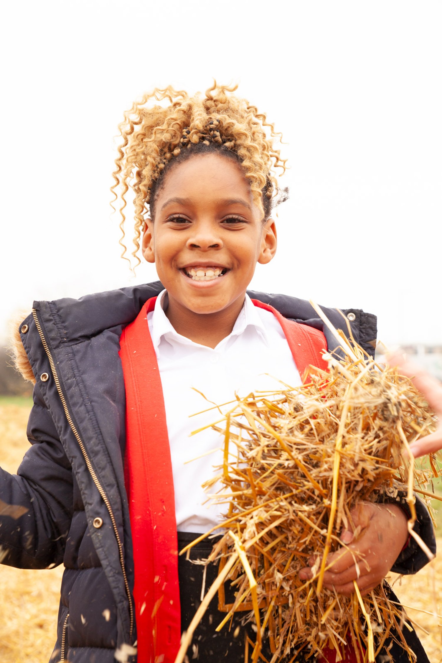a girl holds hay and smiles