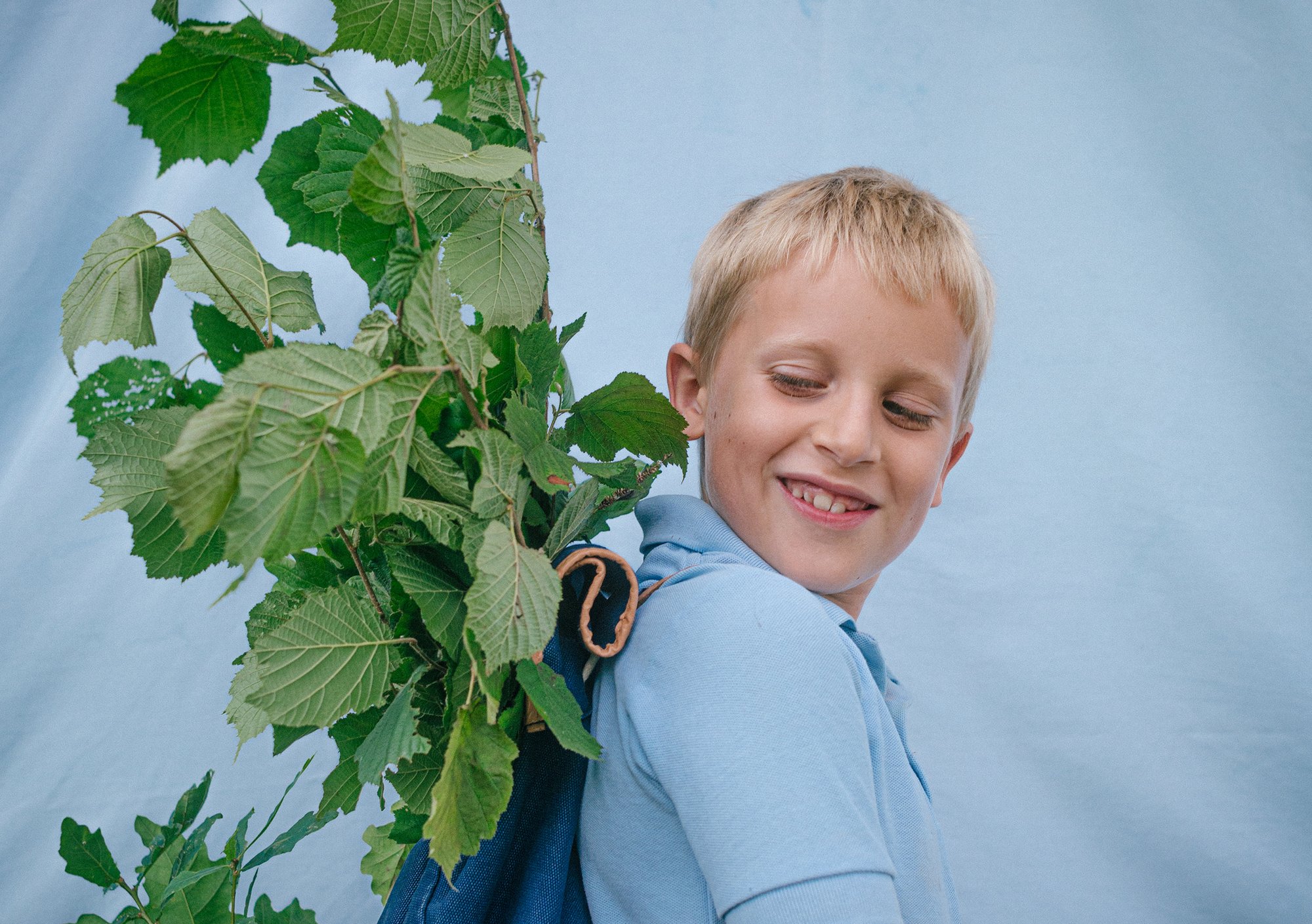 a young boy with a plant in his backpack