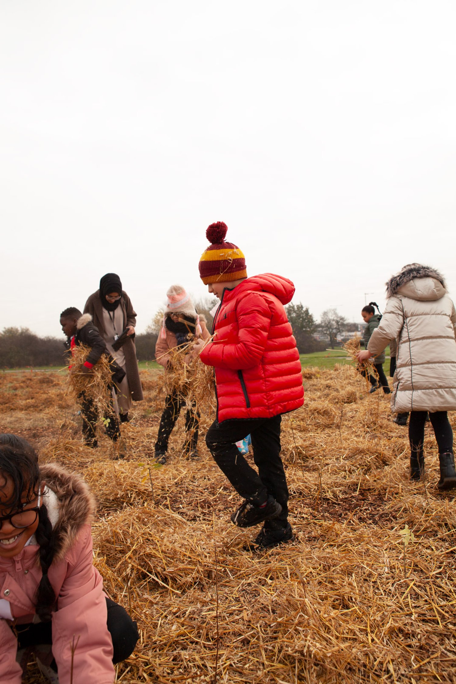 children walk through a field with hay