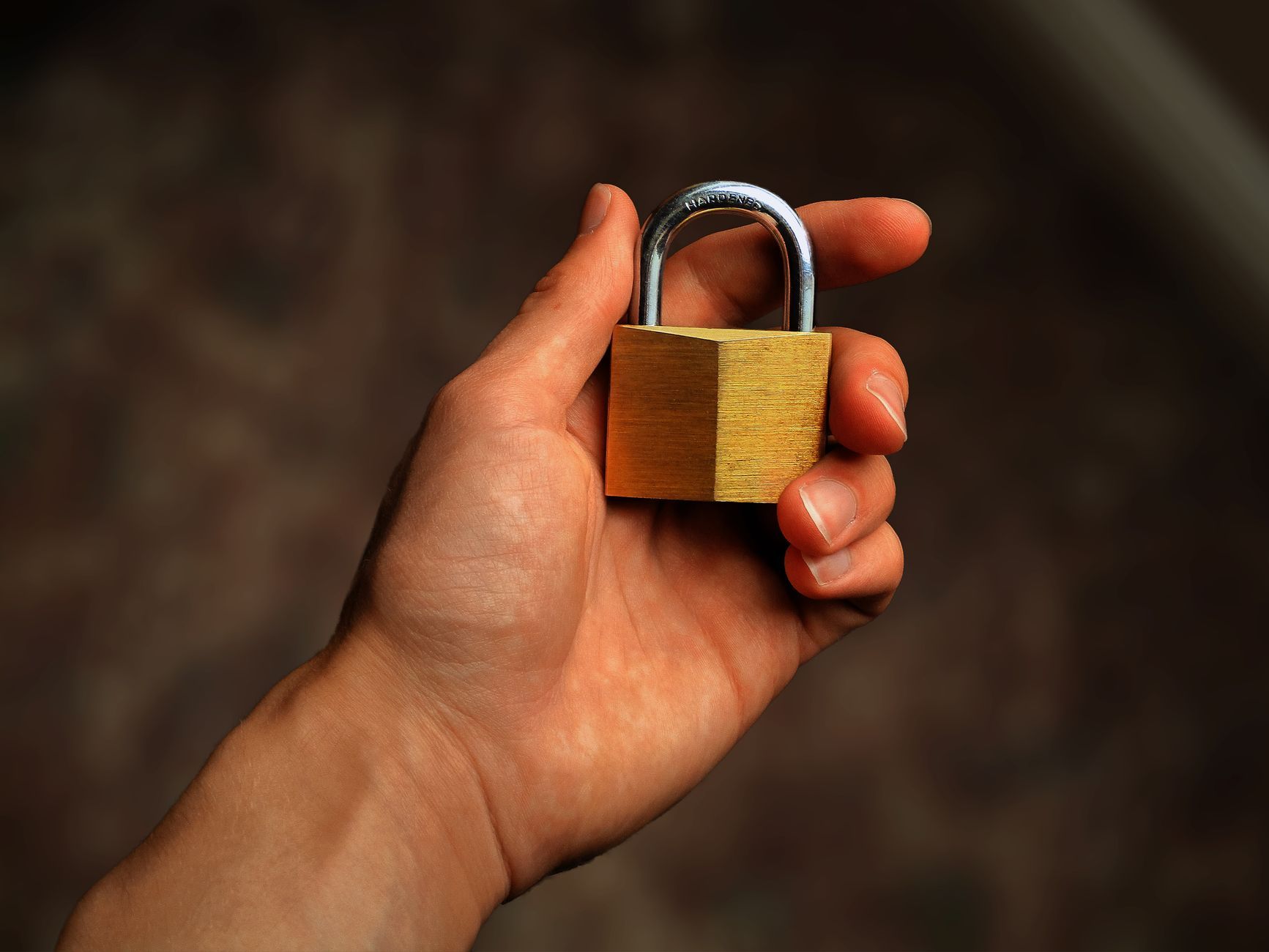 Hand holding a brass padlock, symbolising security and protection