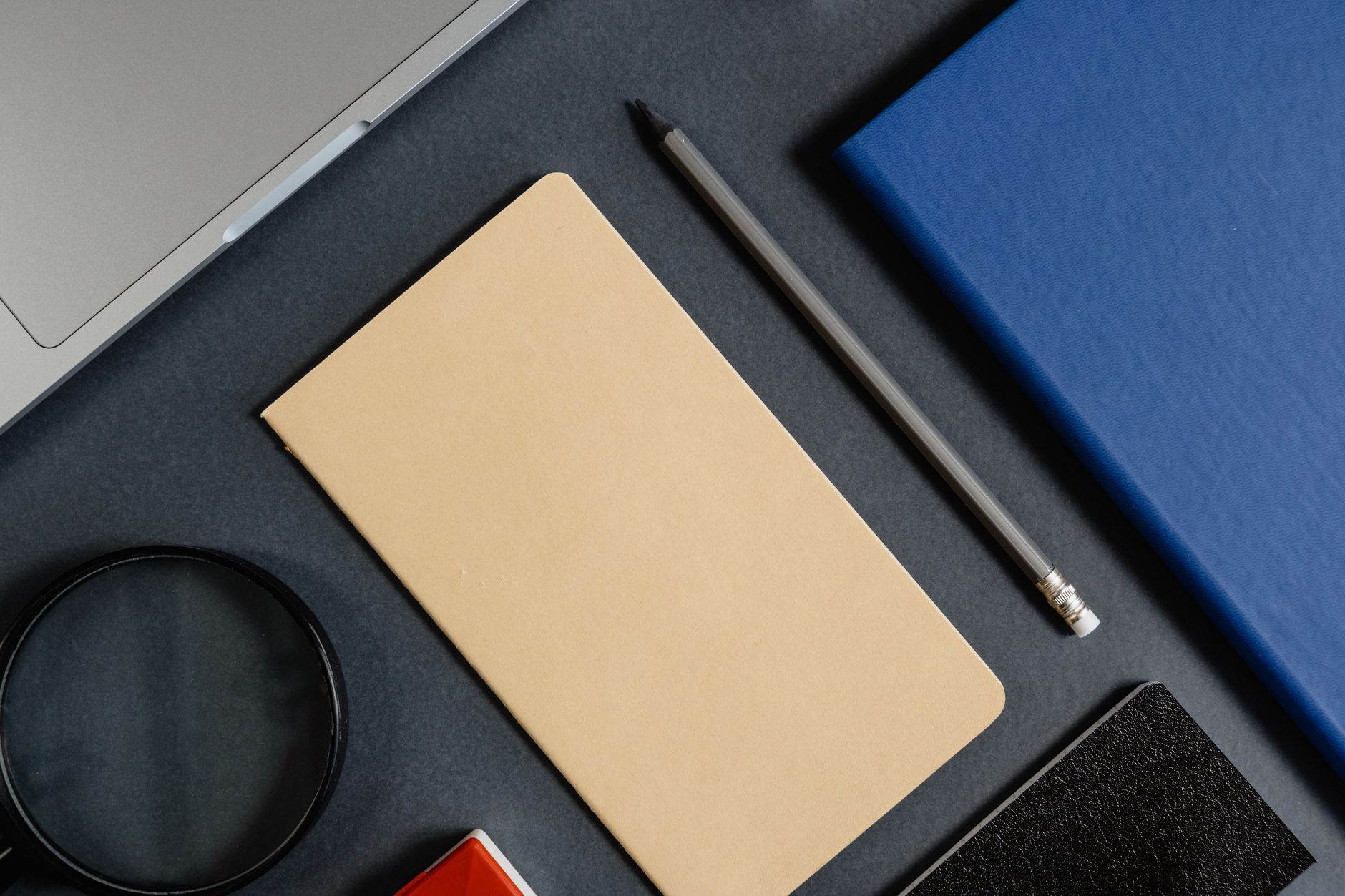 A pencil resting among notebooks on a desk, representing written meeting minutes