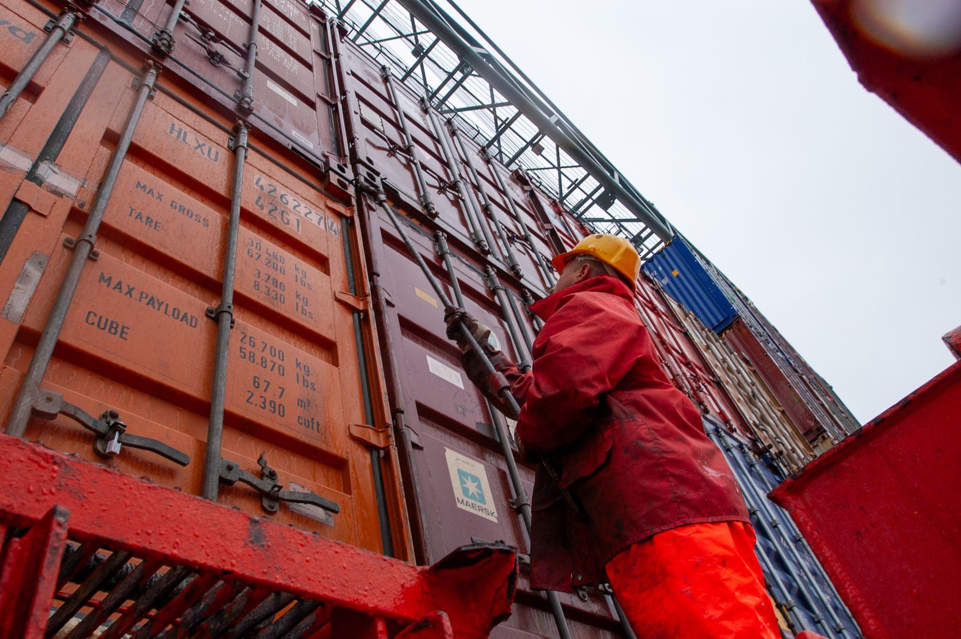 A worker securing cargo containers at a shipping port