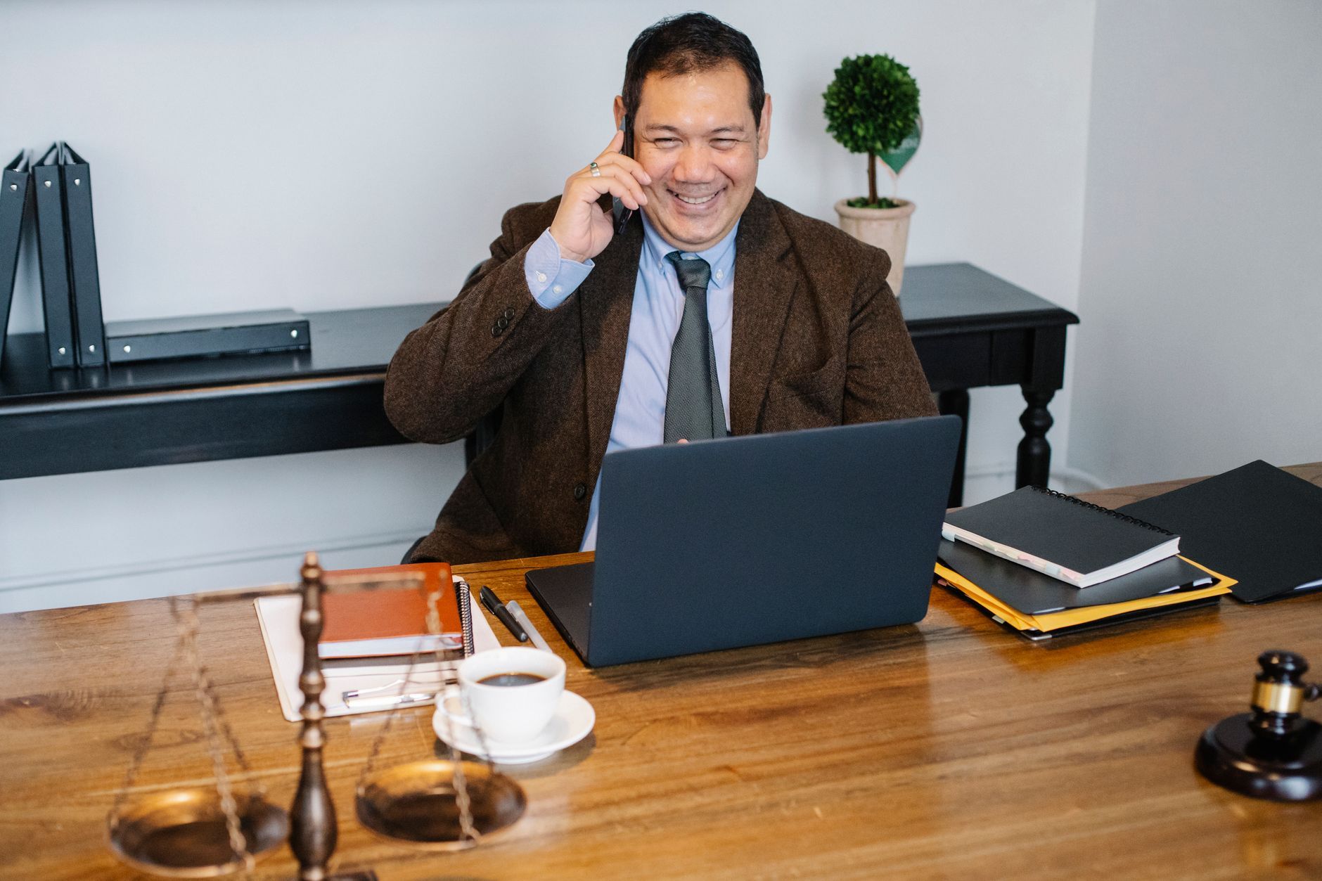 Lawyer on a mobile phone while working on a laptop in a law office