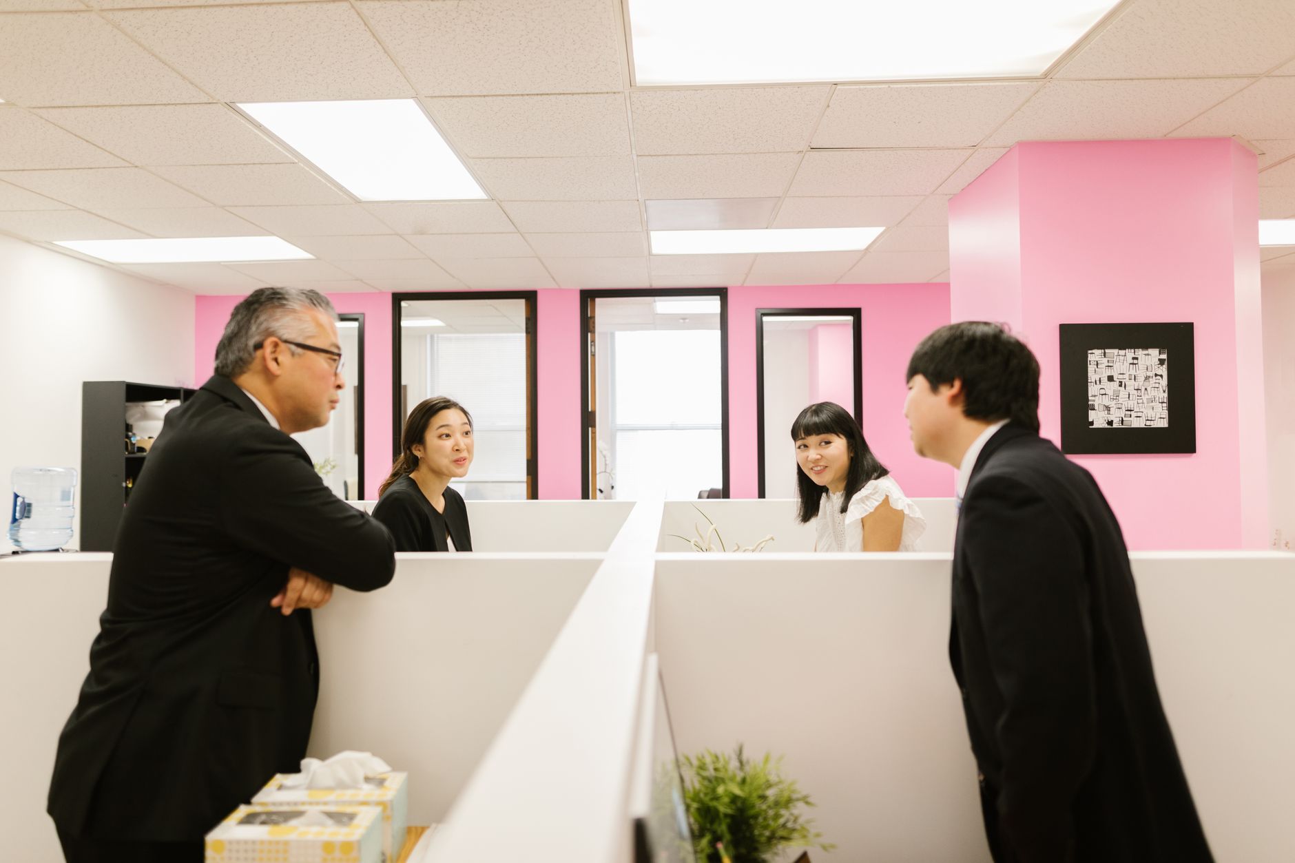Colleagues in a modern Asian office in animated discussion around a desk, representing a Singapore regional office coordinating teams across several Southeast Asian countries