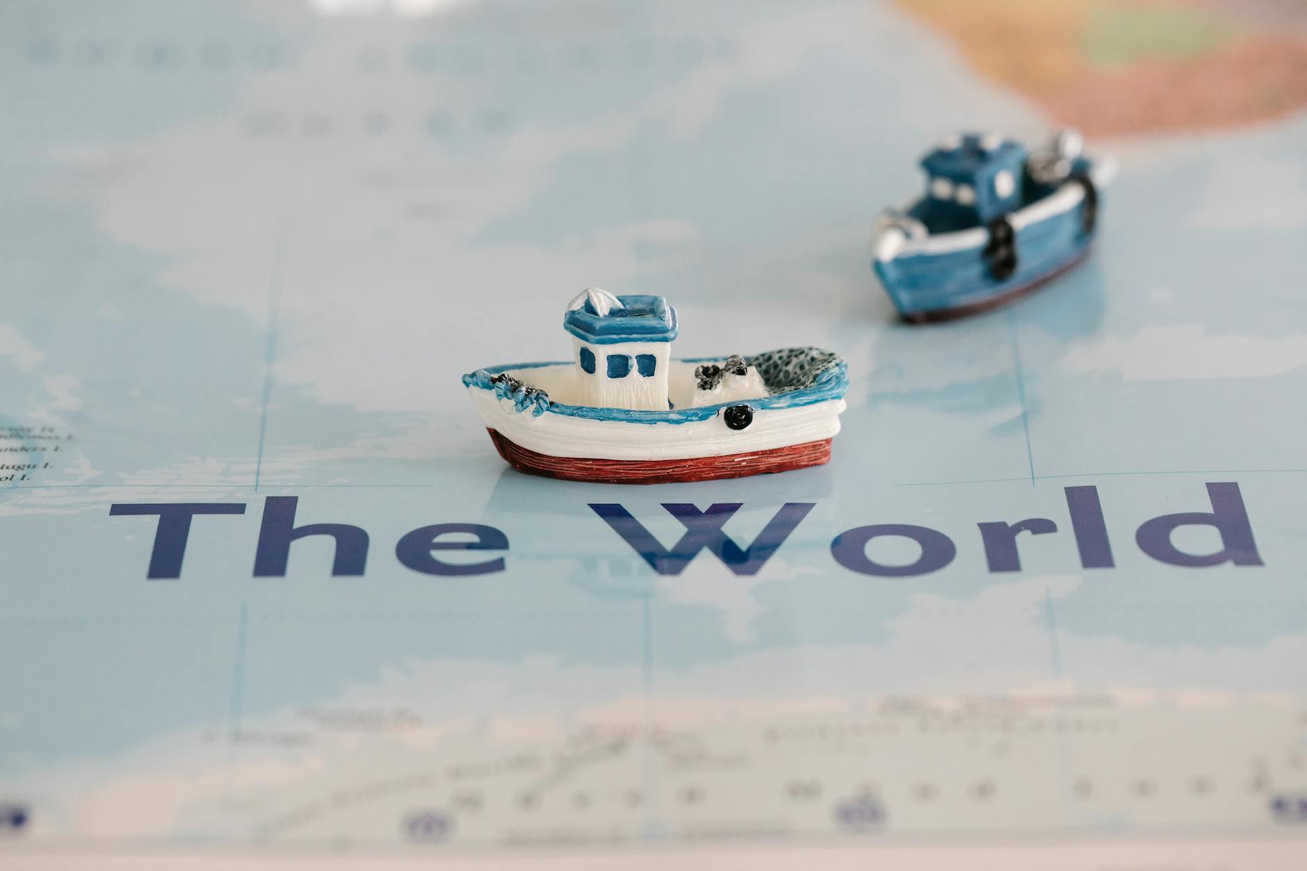 Close-up view of miniature ships placed on a world map, creating a nautical theme.