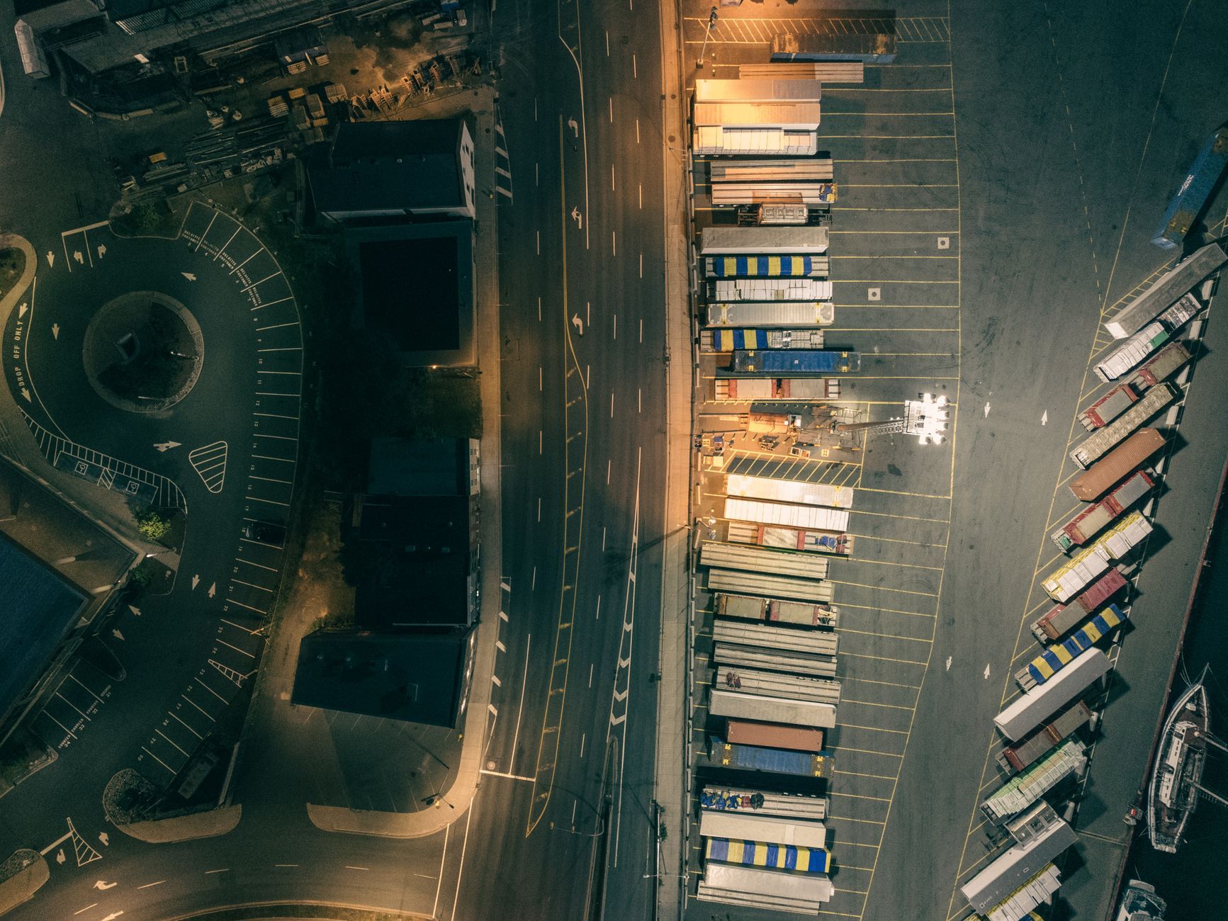 An aerial view of a cargo port at night, containers and access roads lit against the dark, representing a Singapore logistics operation running through the overnight hours