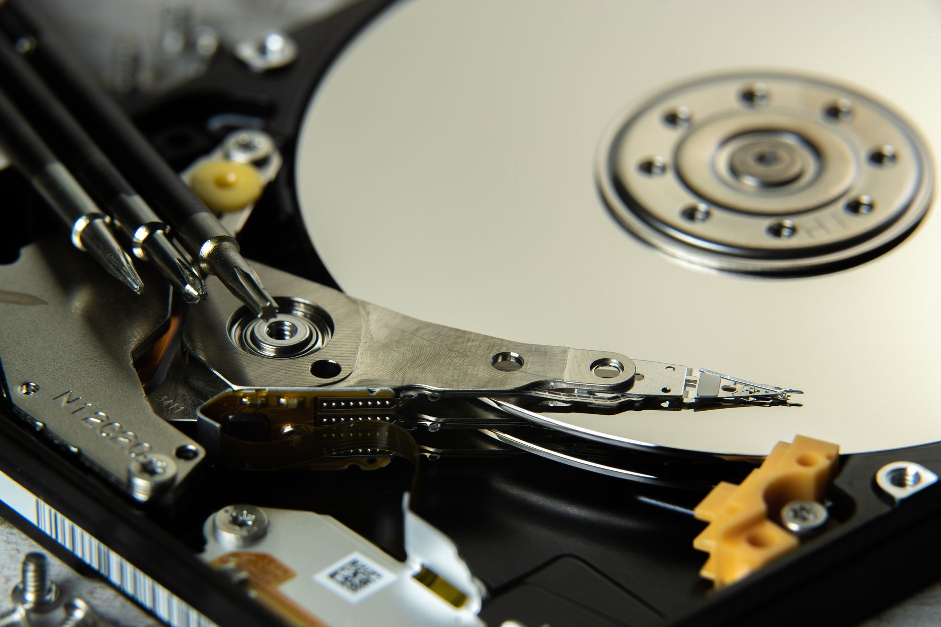 Close-up of the internal platters and read/write heads of an opened hard disk drive — the magnetic surfaces a degausser destroys