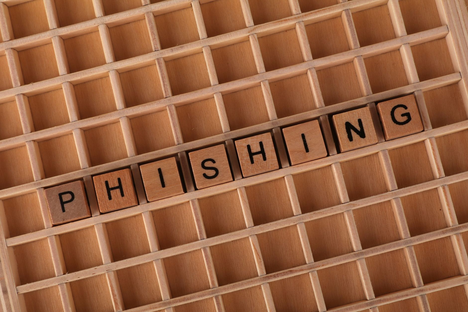 Wooden letter tiles spelling the word phishing, representing security awareness training