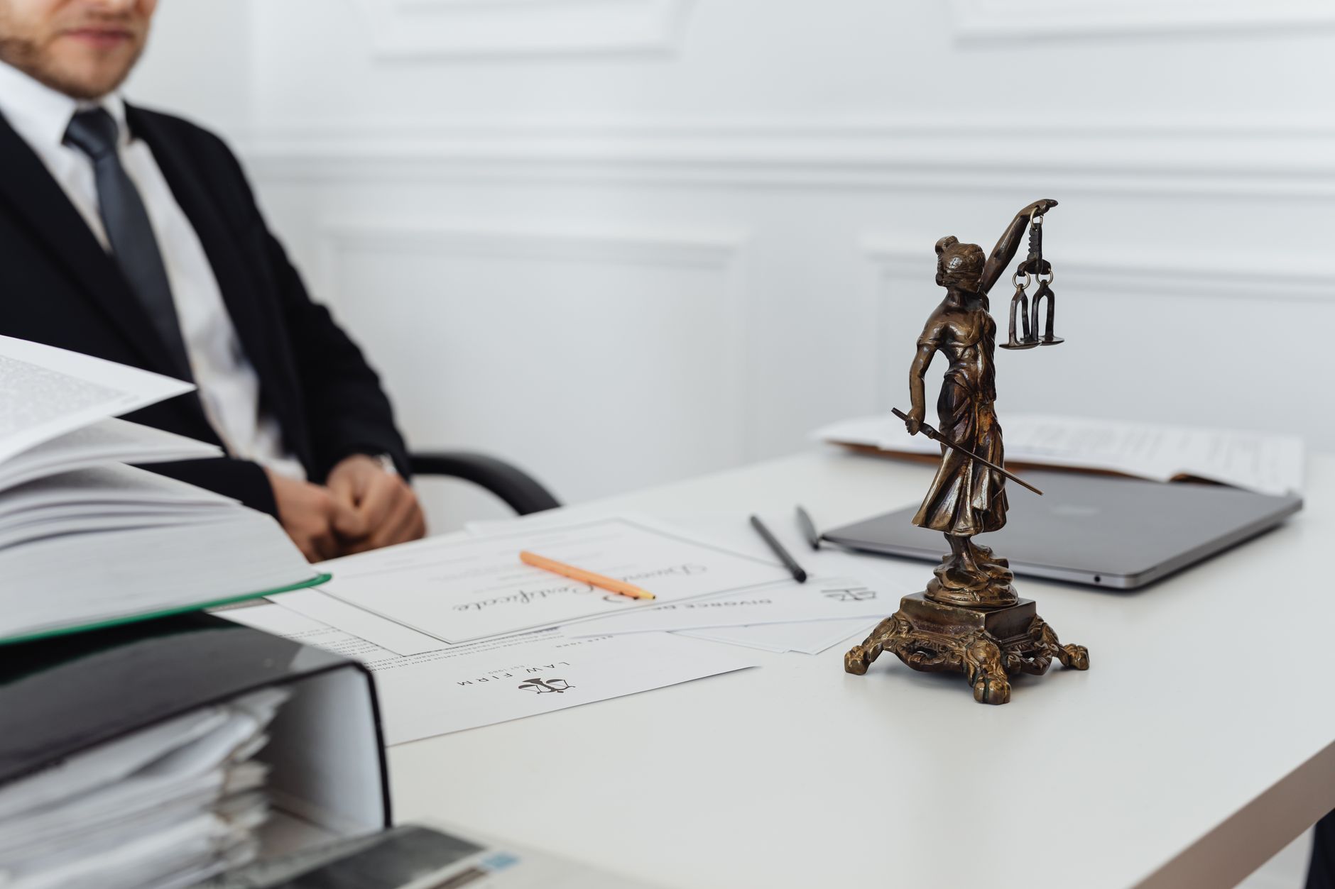 A legal professional's desk with a Lady Justice statue, printed documents and a laptop, representing the intersection of Chinese employment law and IT operations for foreign-invested enterprises