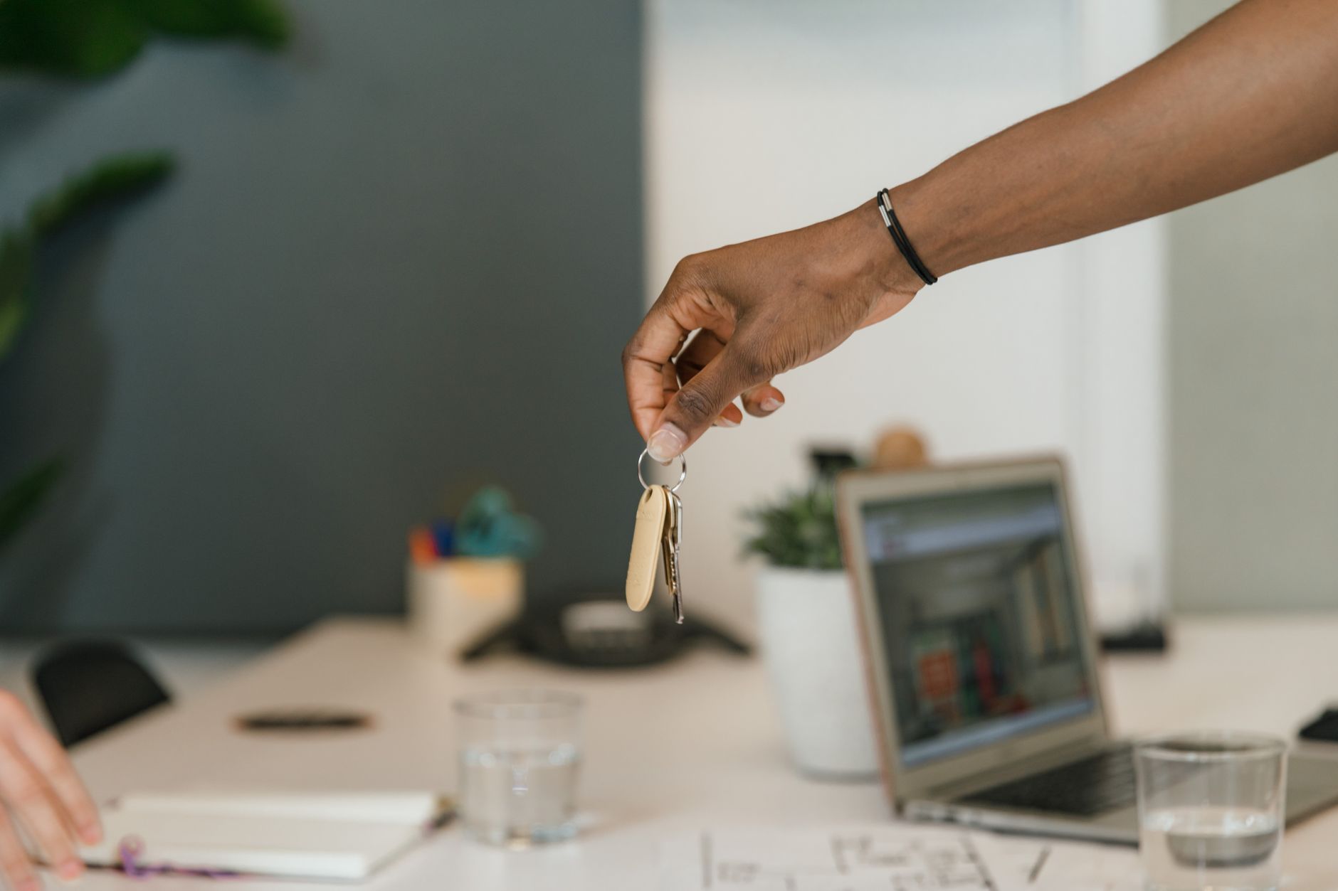 Close-up of two people exchanging keys during a handshake in an office setting, representing a Hong Kong trading company handing over IT operations from an outgoing provider to a new managed IT team