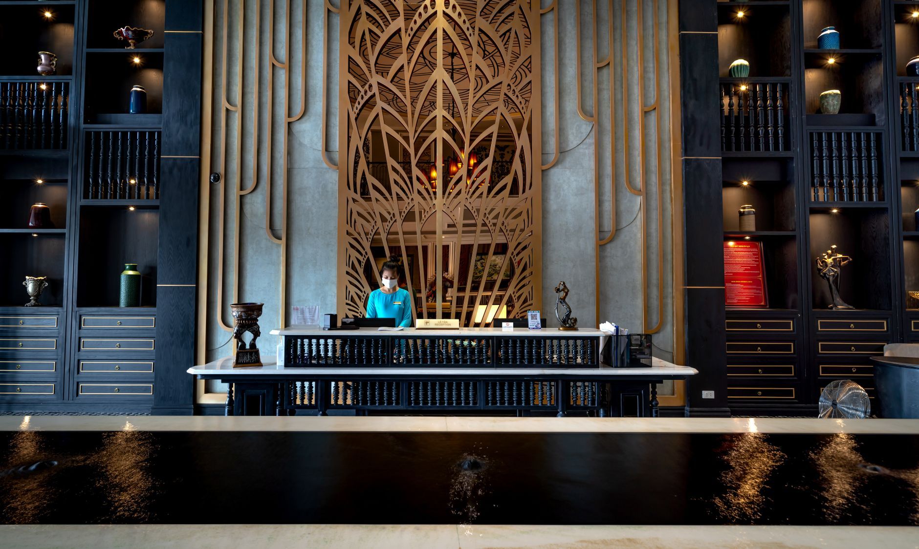 A hotel reception desk staffed at the front of a modern lobby, representing the four always-on properties a single IT manager was holding together