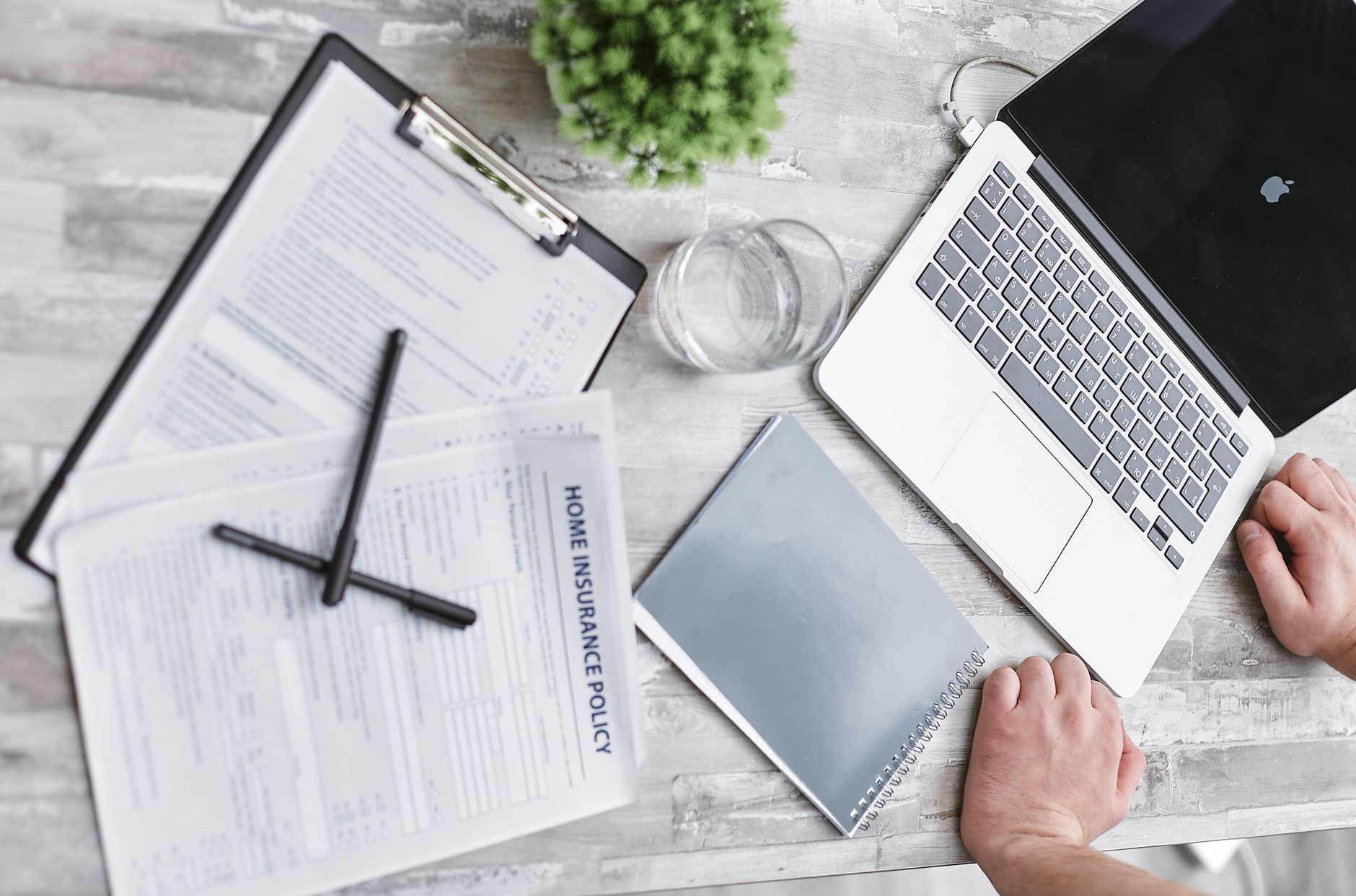 Insurance renewal paperwork, a laptop and documents laid out on a desk, representing a Hong Kong SME working through a cyber-insurance renewal questionnaire