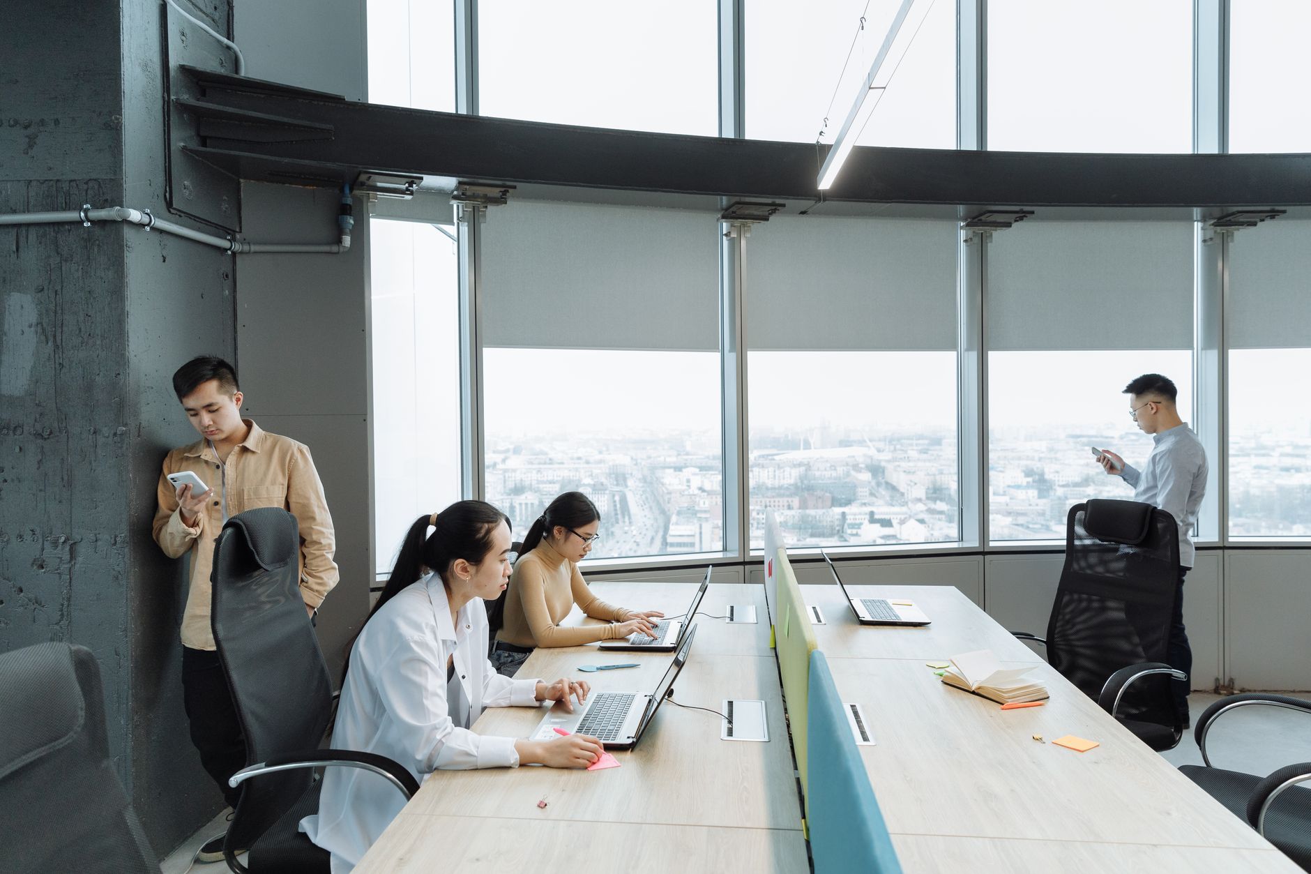 Professionals working on laptops and phones on an upper floor of a city office, the kind of multi-floor workplace where every client call depends on the wireless network