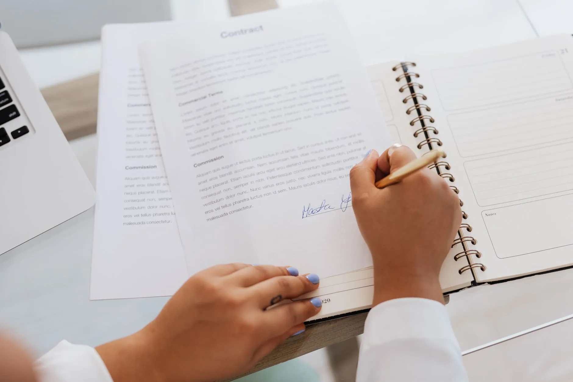 Hands signing a services contract at a desk — the renewal moment when an IT SLA's measurement rules, service credits, exit terms and any performance bond are either written in or left out