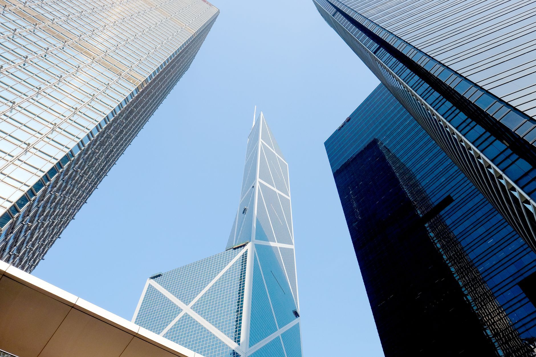 Upward view of Hong Kong's Central financial district skyscrapers against a clear blue sky, representing the banks and regulated institutions HKMA's cyber resilience and outsourcing rules govern