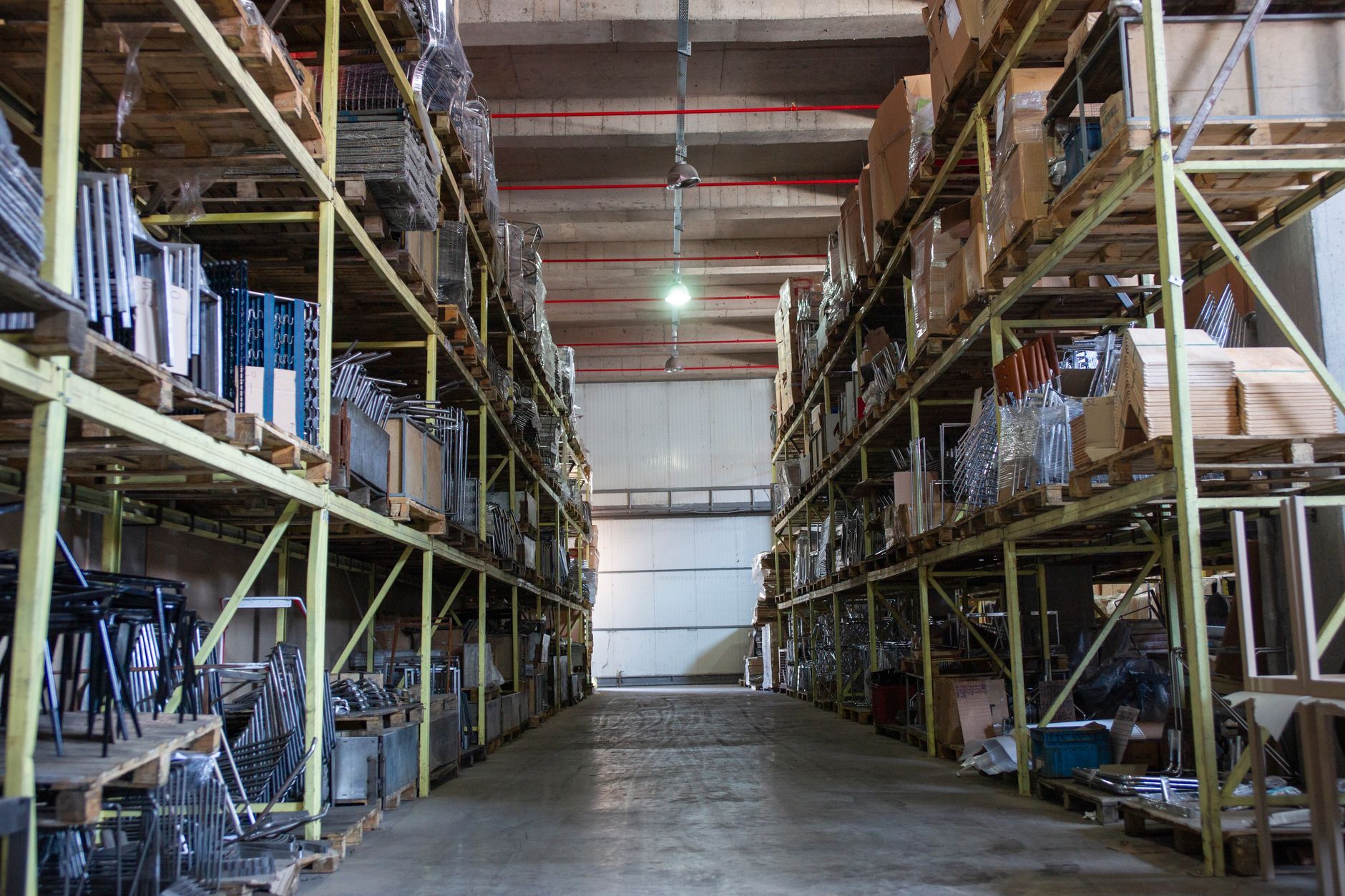 A wide aisle between two tall runs of industrial steel shelving in a warehouse — the physical environment where handheld scanners lose their connection and no controller setting can fix it
