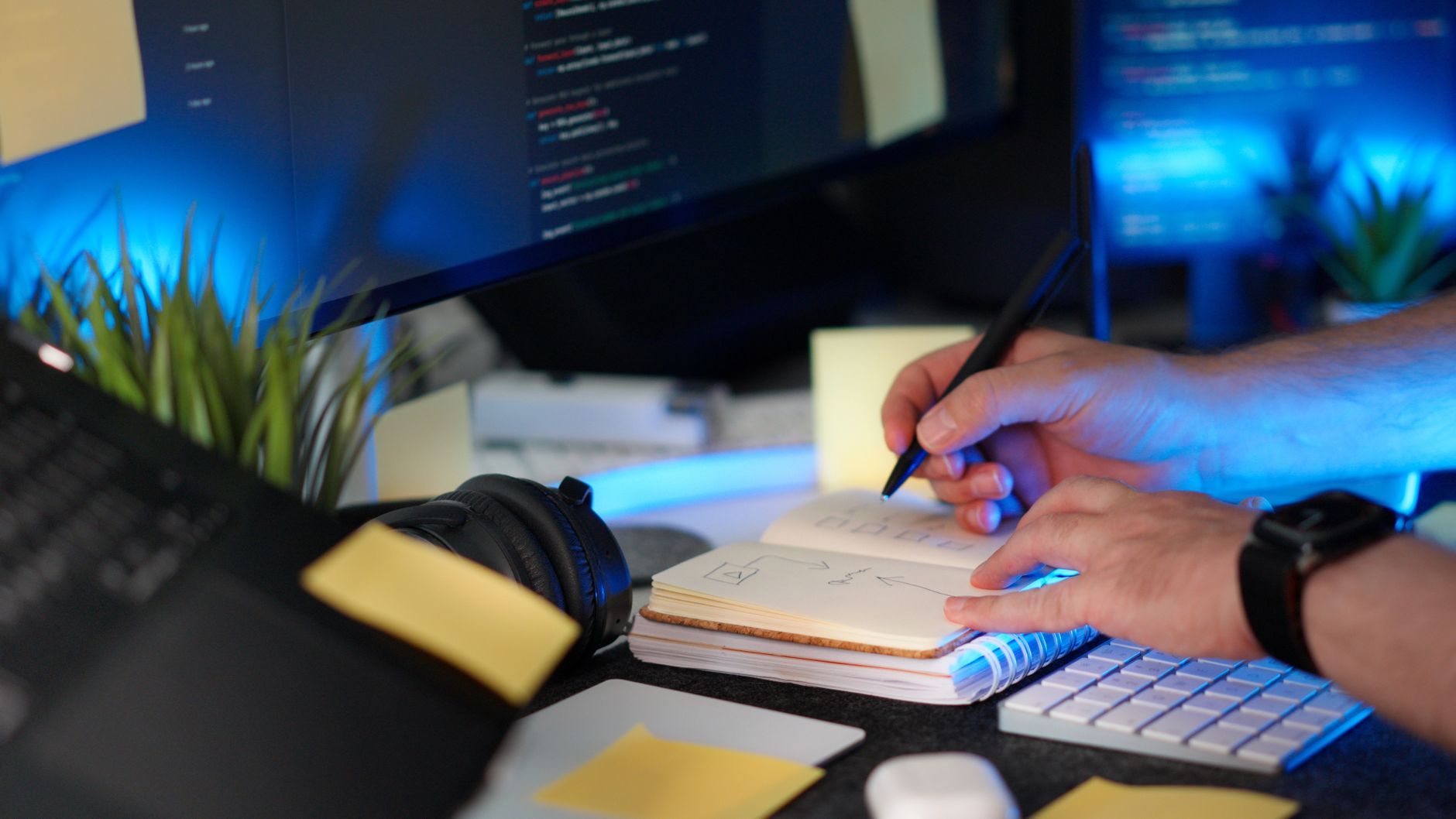 A person planning an IT project timeline with handwritten notes beside a monitor, representing a 90-day IT readiness plan for a new China WFOE