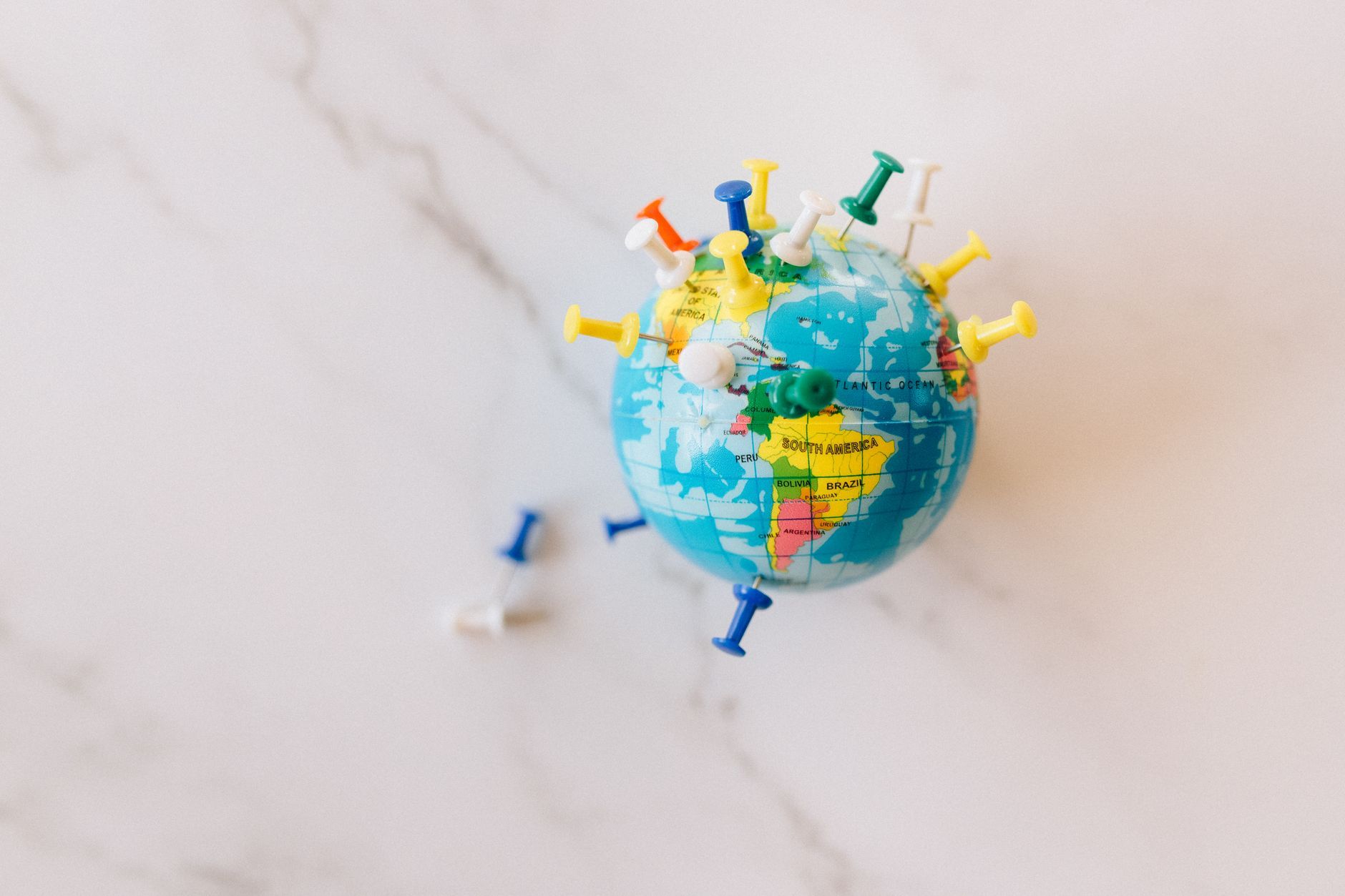 A globe marked with colourful push pins, symbolising coverage across many cities