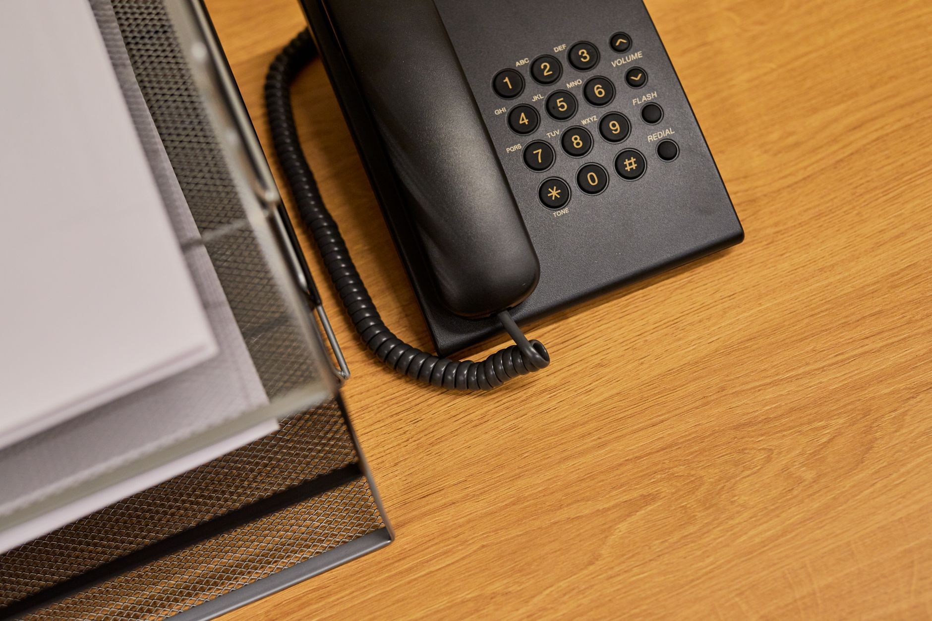 A desk telephone and a document organiser on an office desk, representing a business phone system