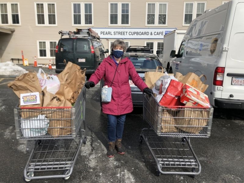 Woman holding two full shopping carts full of food with Souper Bowl of Caring logo