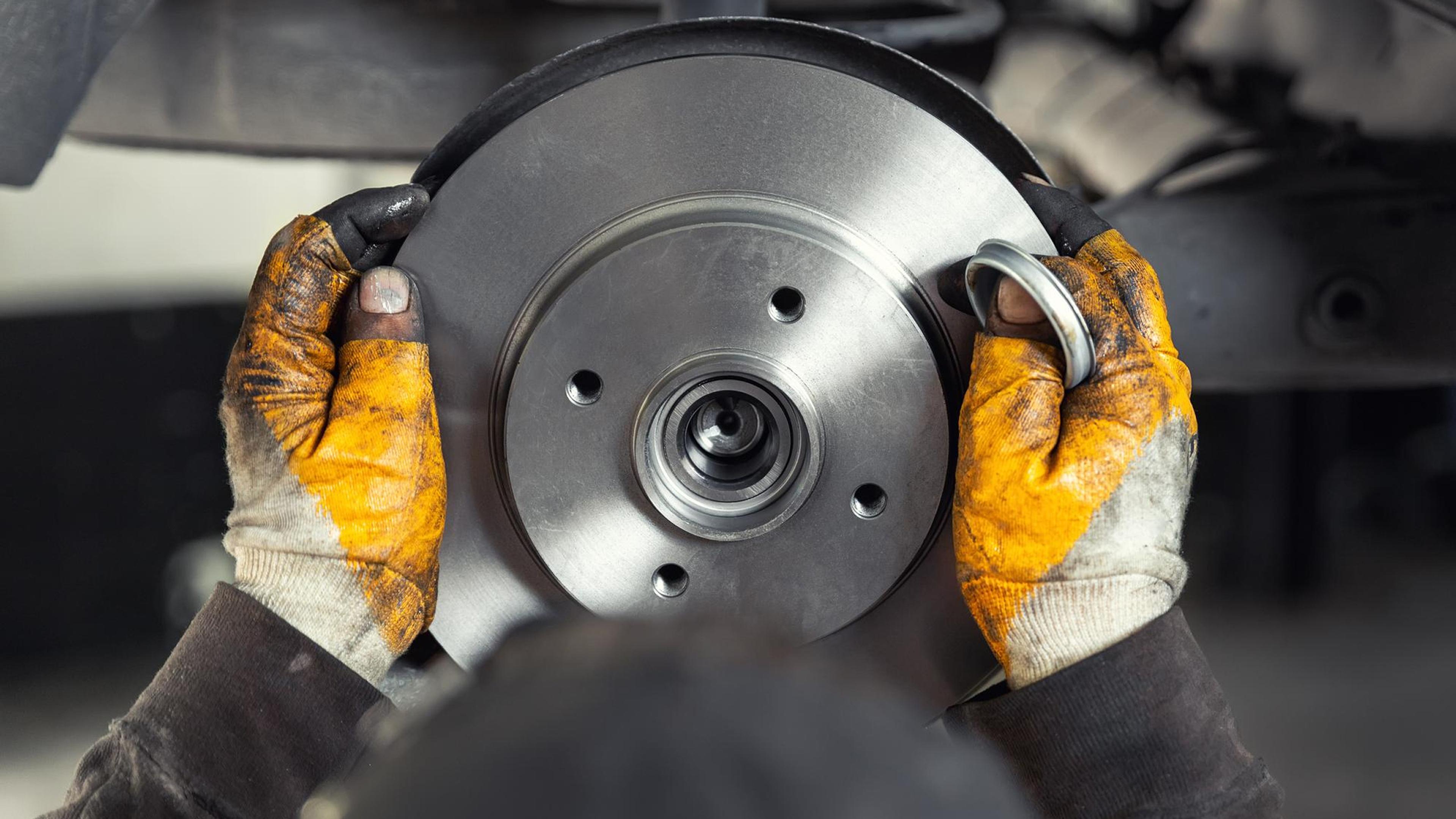Mechanic precisely installs a new brake disc with wheel hub on the axle