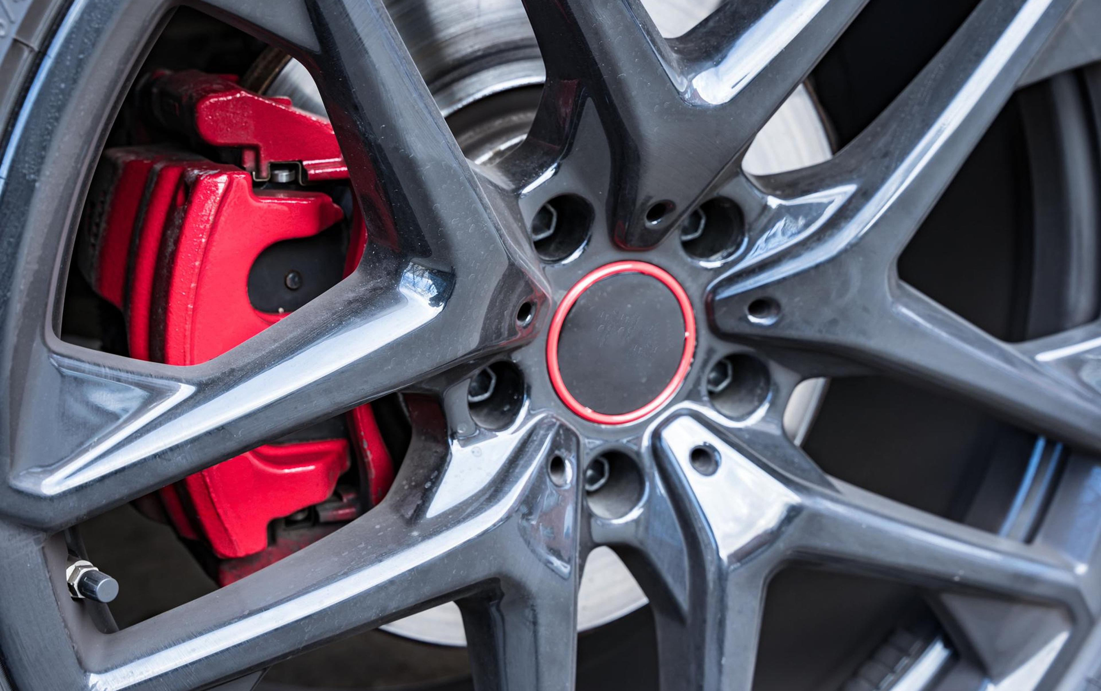 Red brake caliper and brake disc visible behind a modern aluminum wheel rim