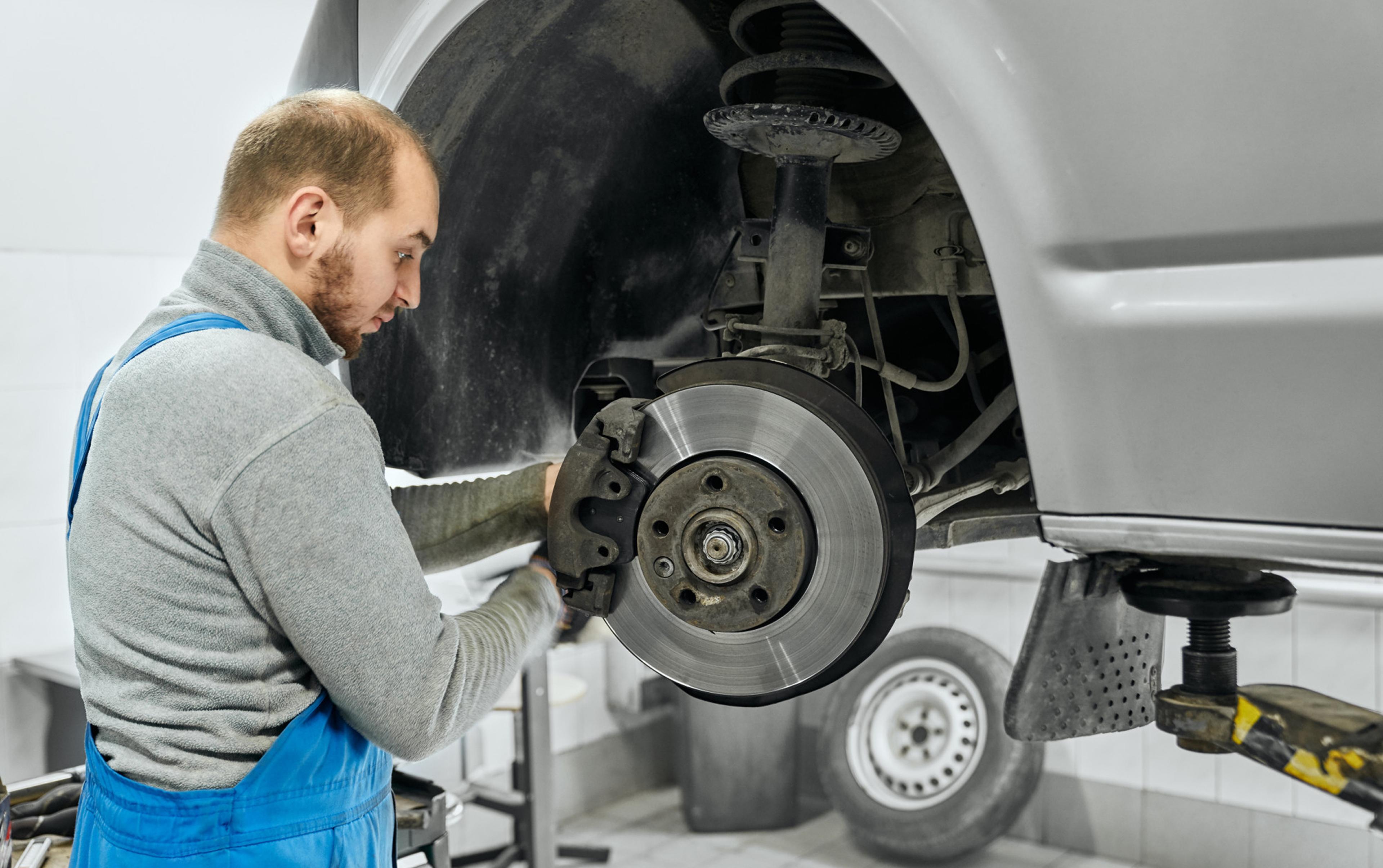 Mechanic installing a brake disc on the front axle of a vehicle in the workshop