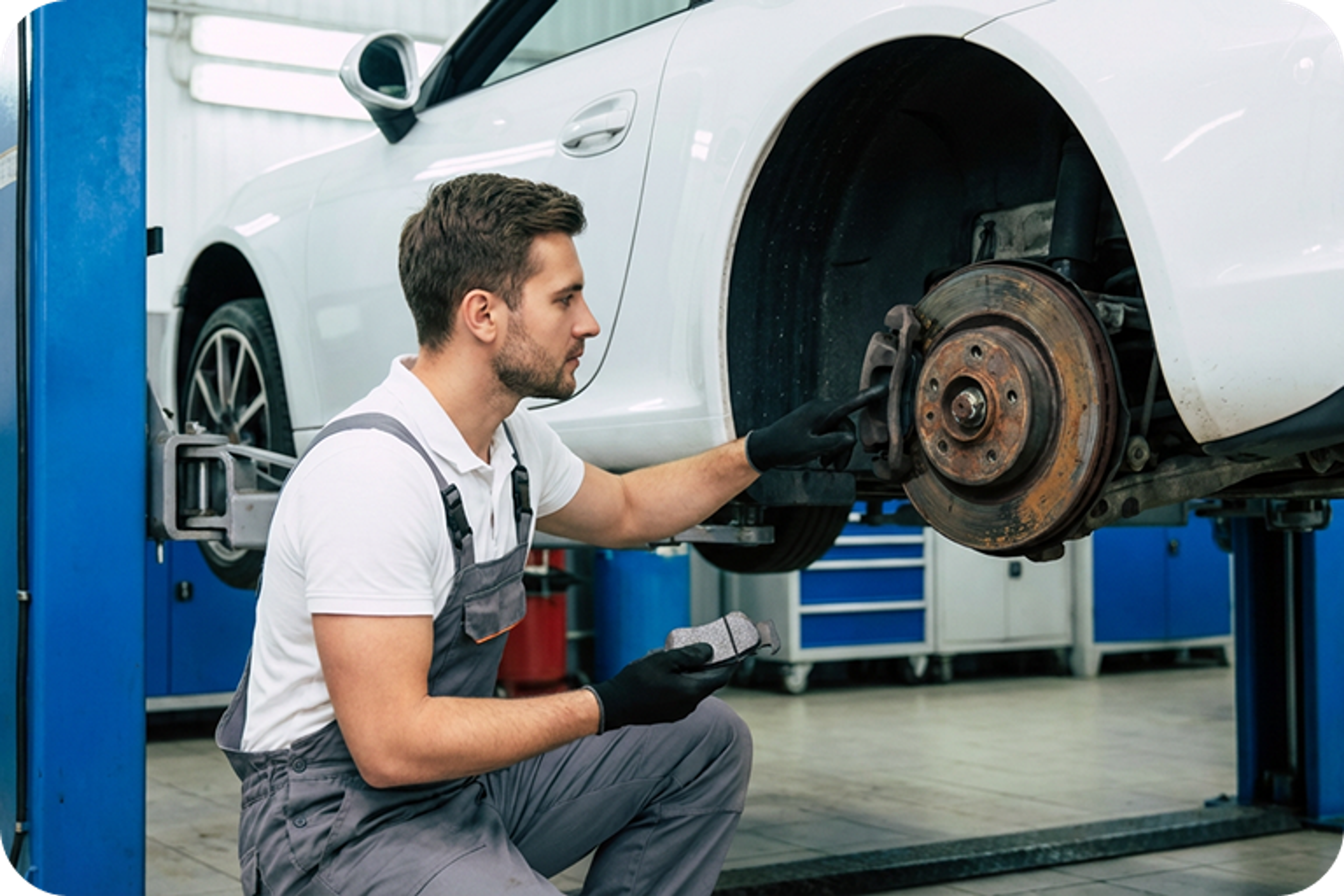 Mechanic inspects the brakes on a raised vehicle in an auto repair shop