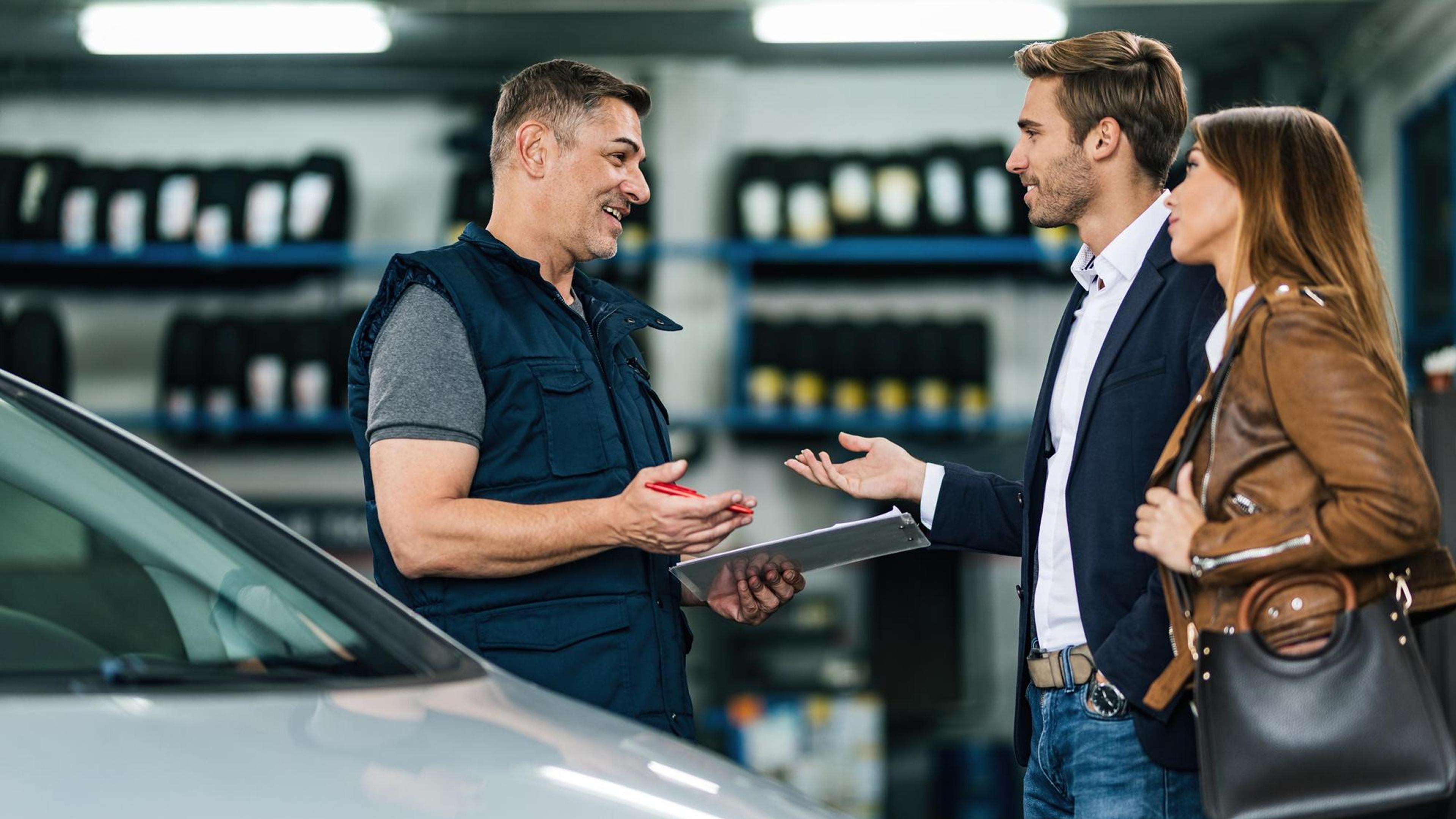 Mechanic explaining repair details to a customer in a car workshop