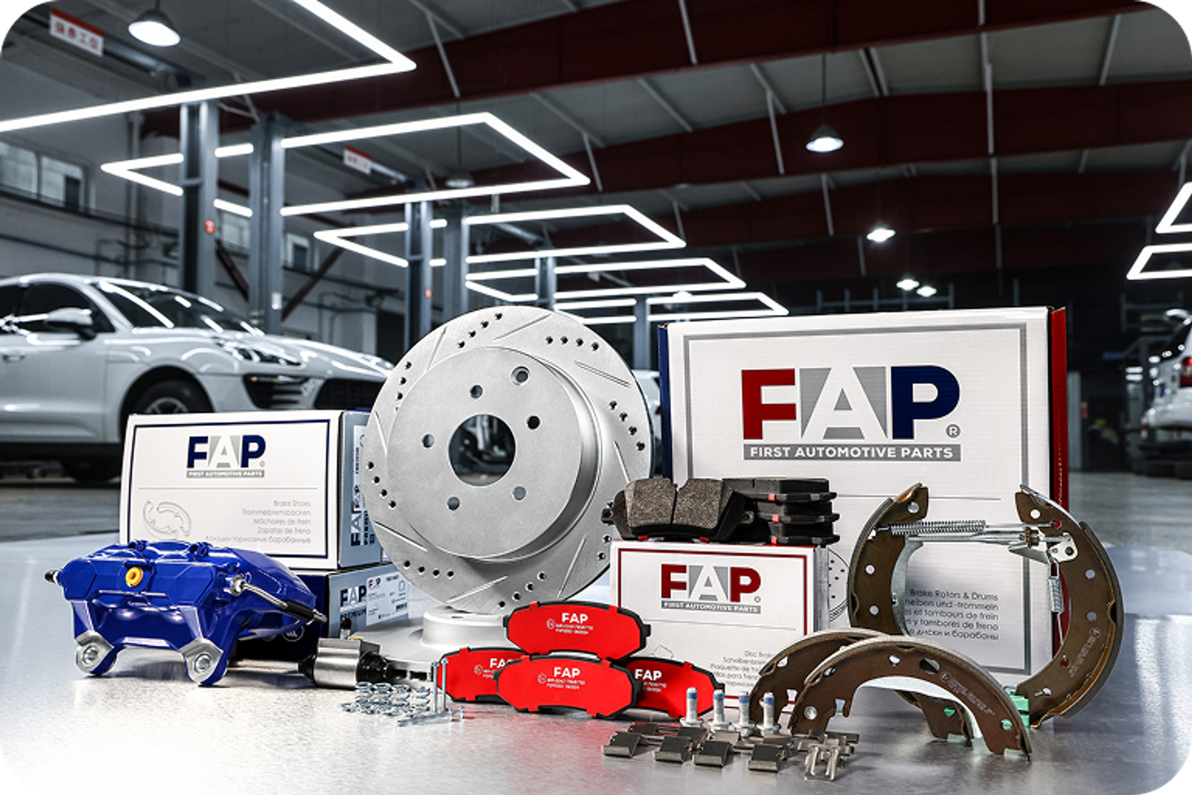 FAP brake components such as brake discs, brake calipers, brake pads, and drum brake parts, presented in a modern automotive workshop.