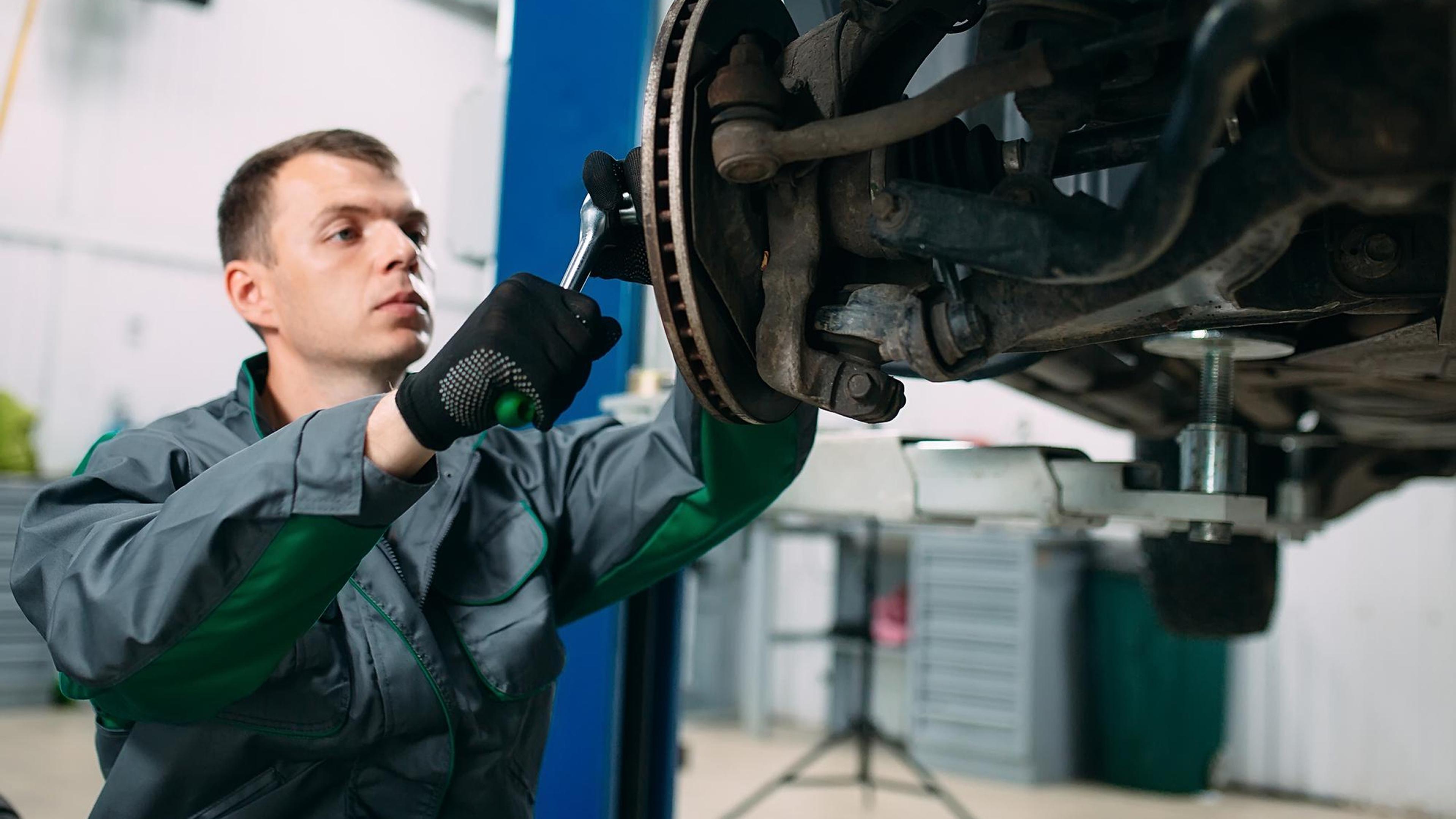 Mechanic tightens screws on the brake system of a vehicle on the lifting platform