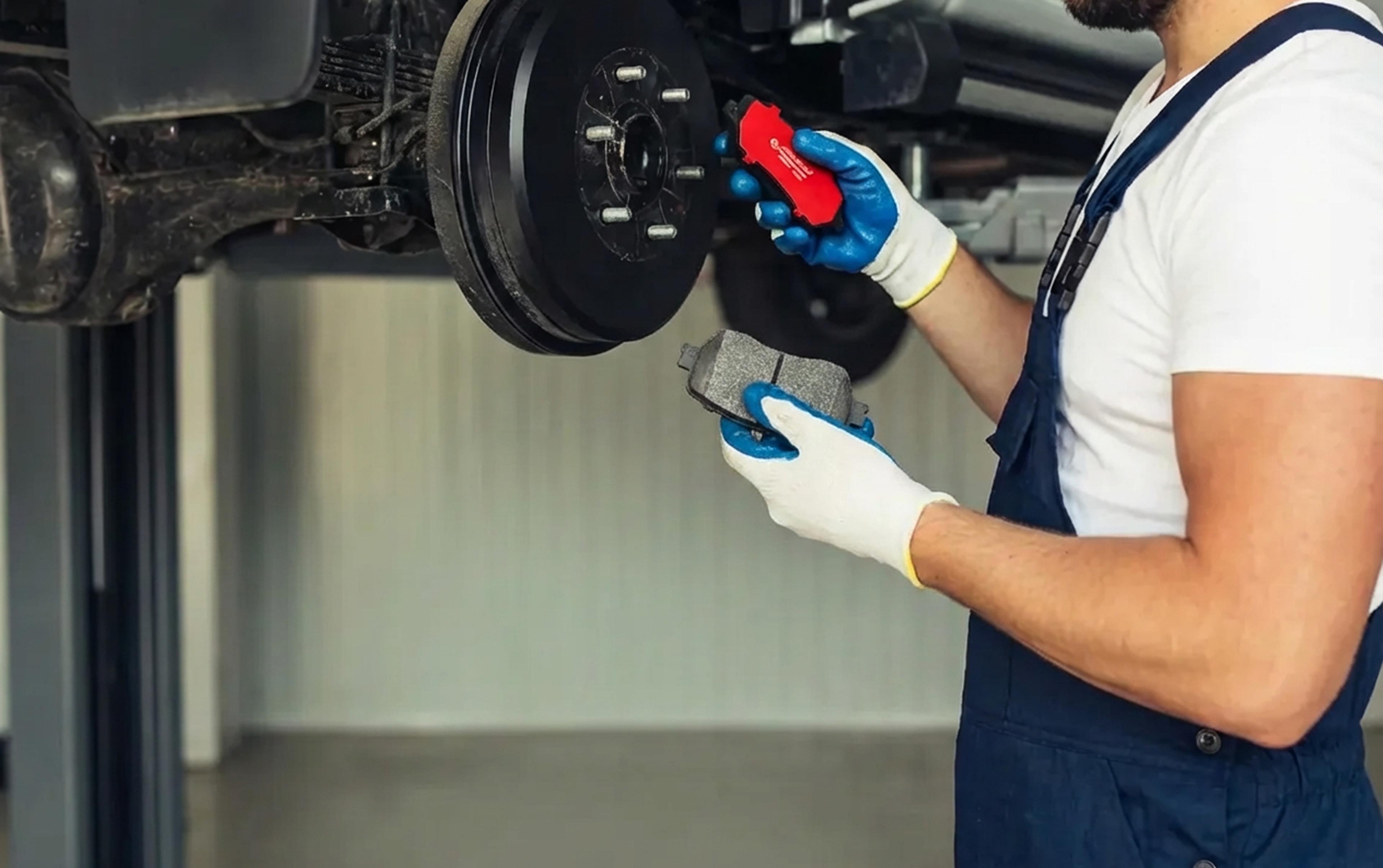 Automotive mechanic holds new brake pads while replacing the disc brake.