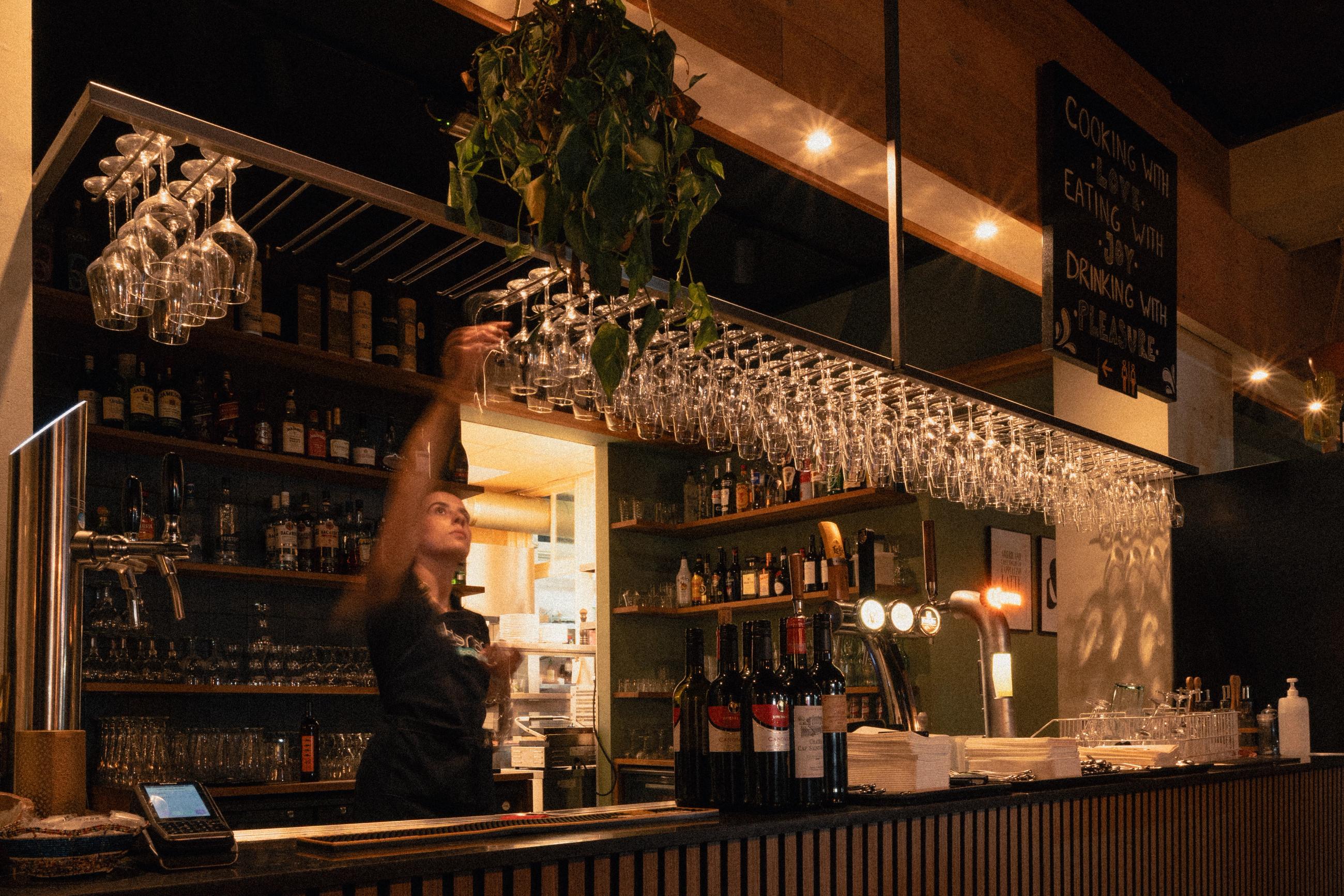 Medewerker van Karaf hangt wijnglazen op achter de bar van het restaurant in Utrecht