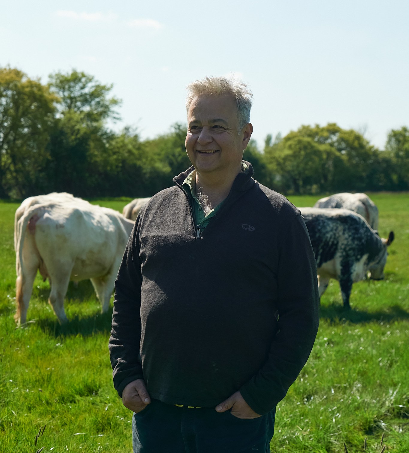 Monil farmer smiling at cows 