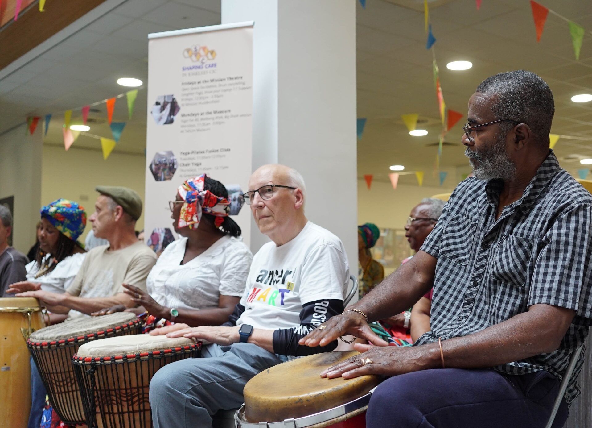 Participants seated in a circle playing djembe drums at Caribbean Kaleidoscope