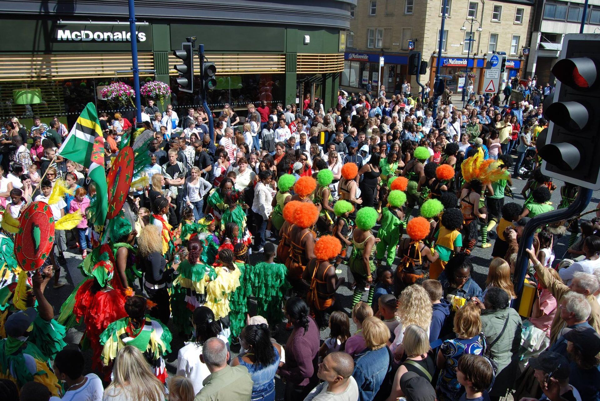A vibrant carnival parade with green, orange and yellow costumes.