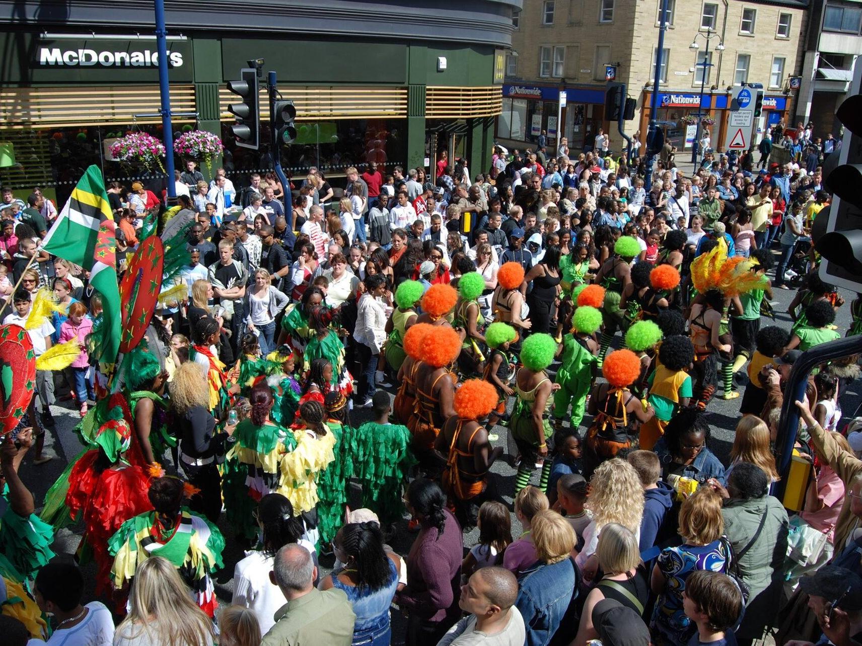 A vibrant Carnival parade with green, orange and yellow costumes.