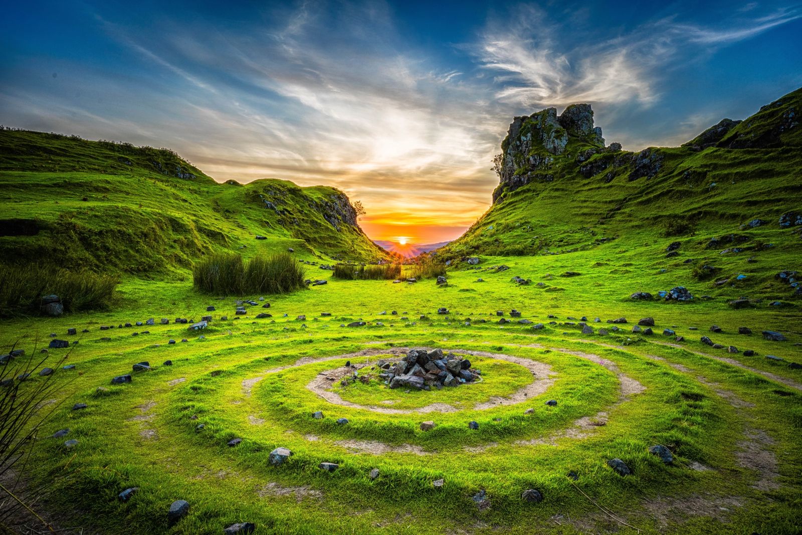Spiral of stones in a green valley at sunset
