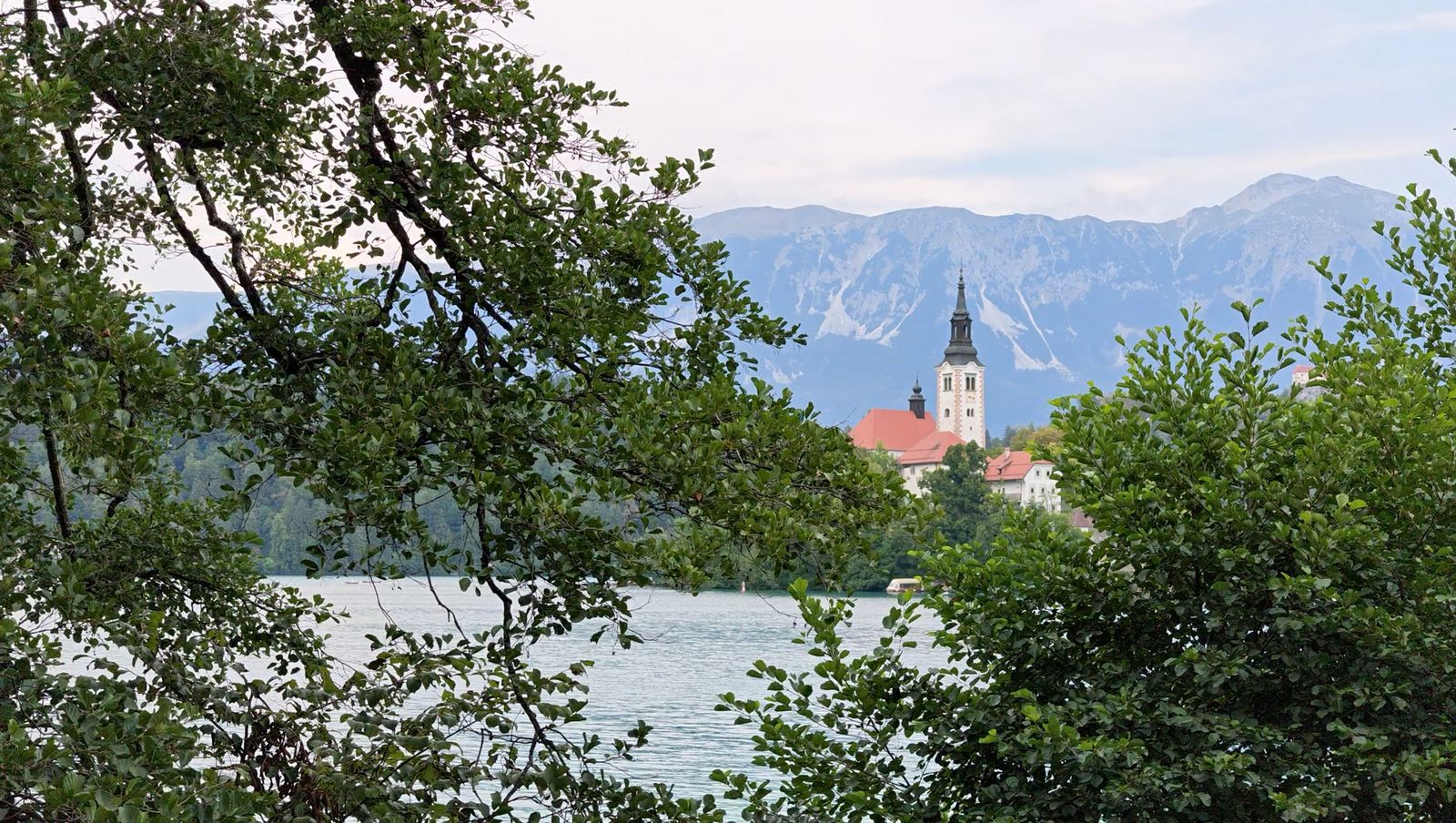 Church on an island in Lake Bled with mountains behind