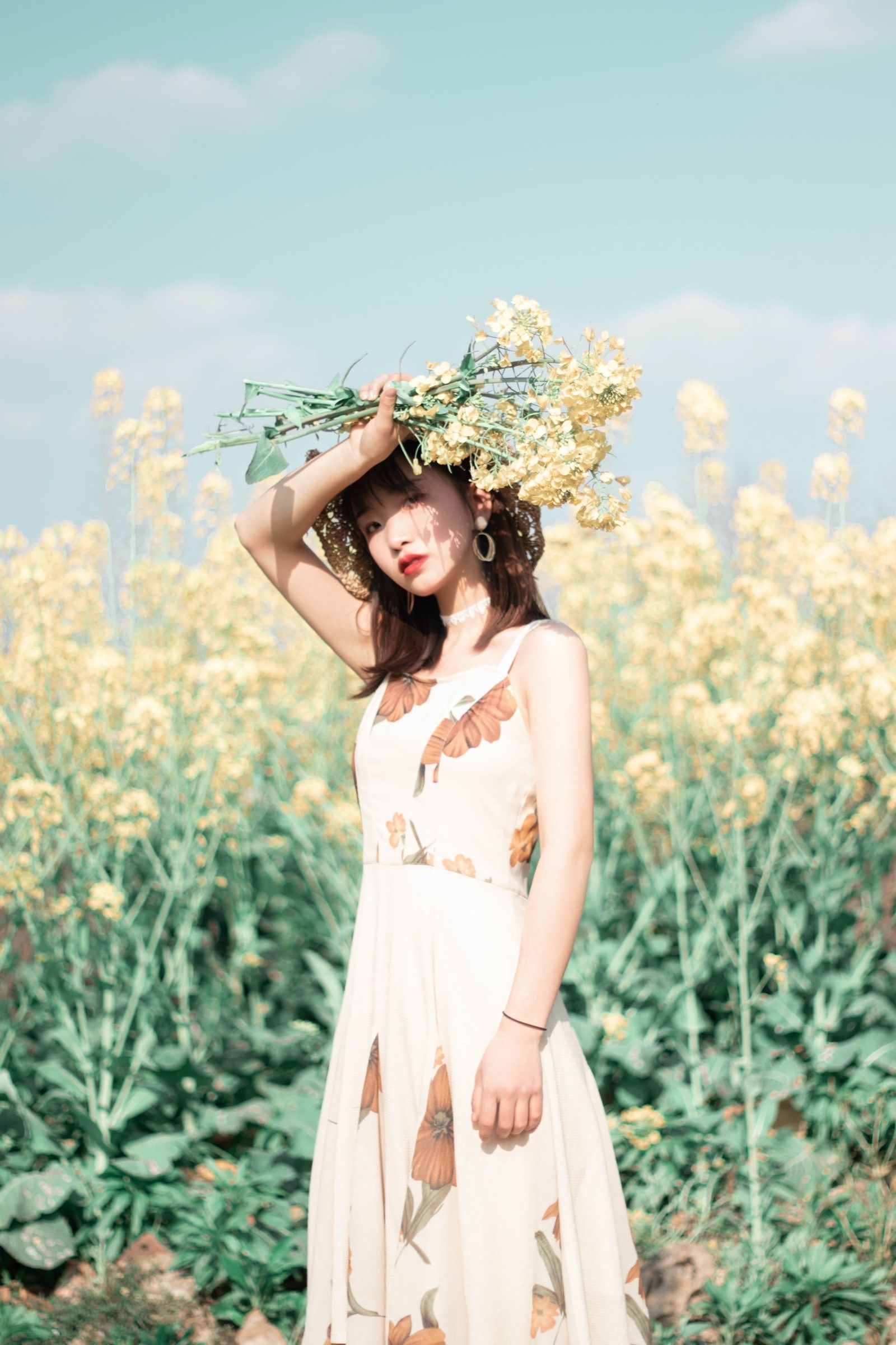 Woman holding a bunch of pale yellow wildflowers above her head