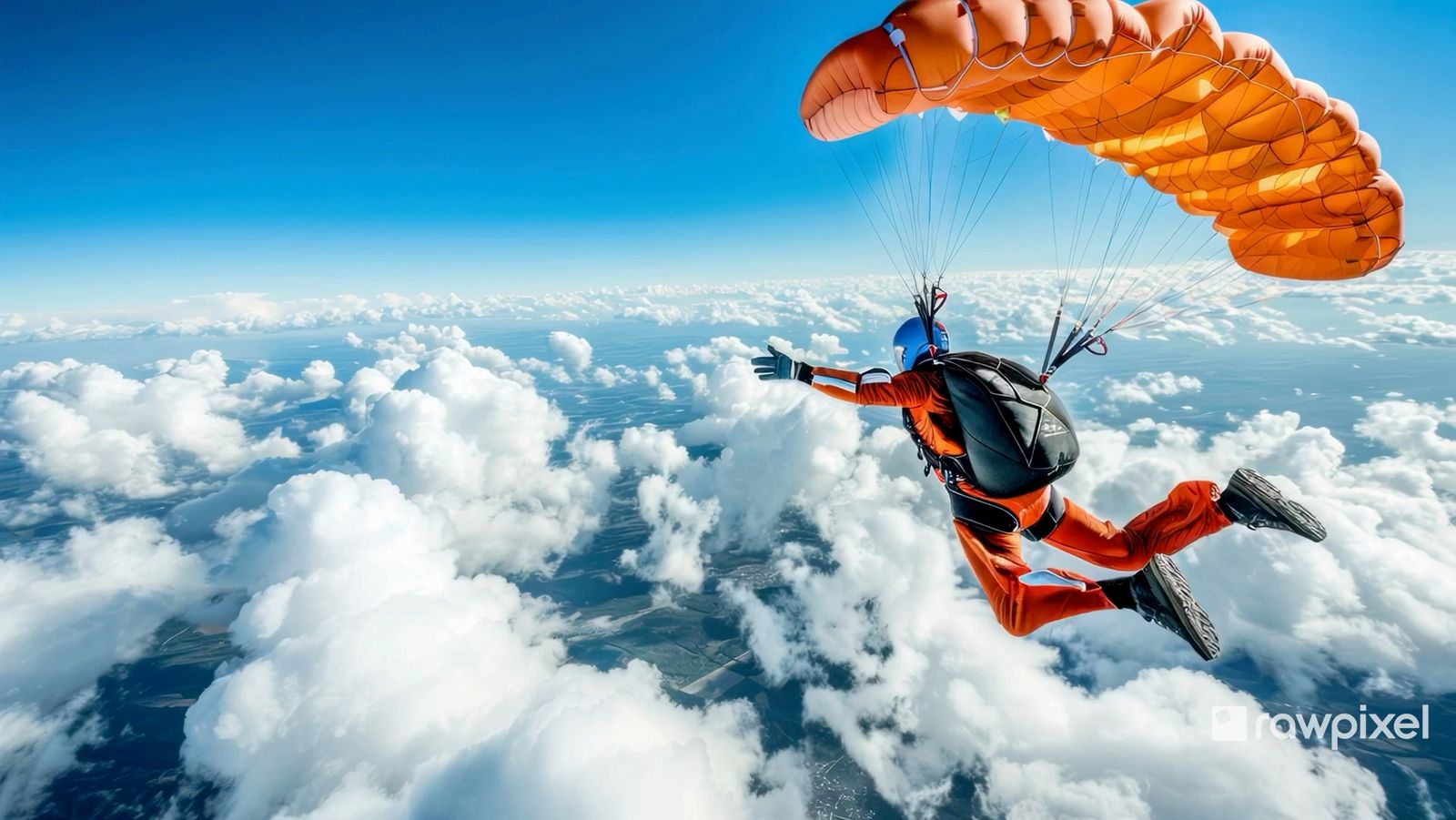 Paraglider with an orange wing flying above the clouds