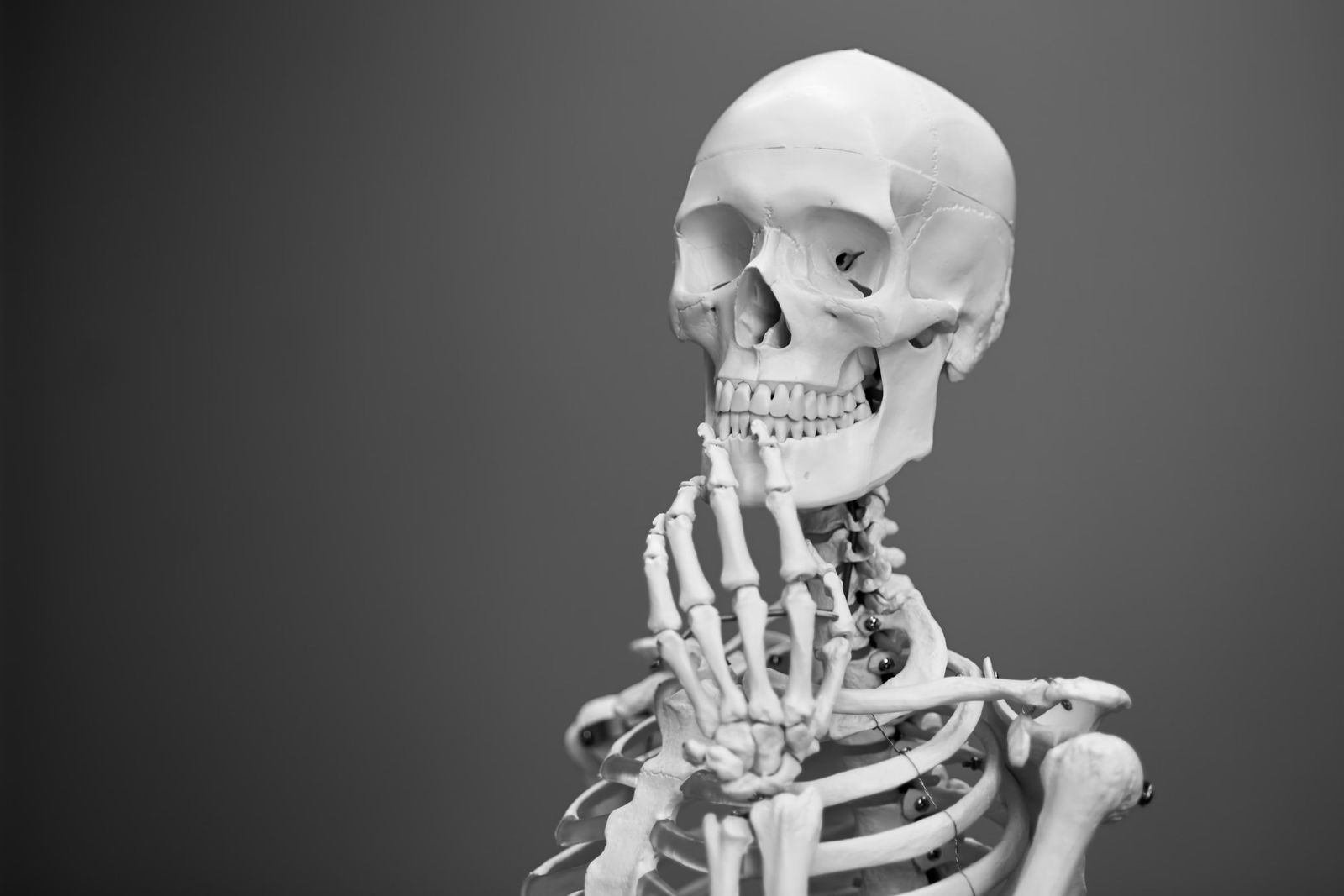 Skeleton in a thinking pose on a dark background
