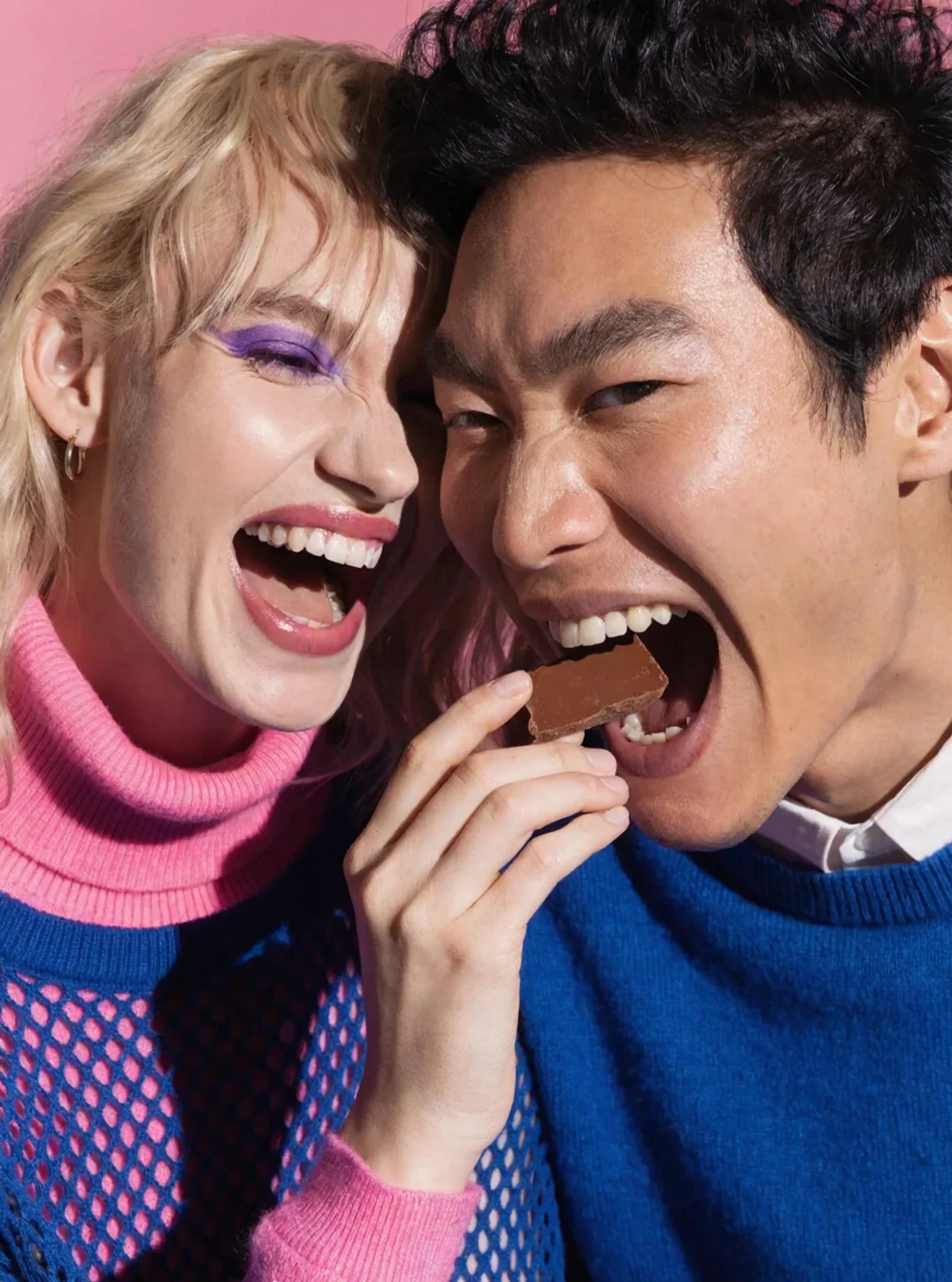 Two people biting into the same ChocoBelly chocolate bar, sharing a tender moment