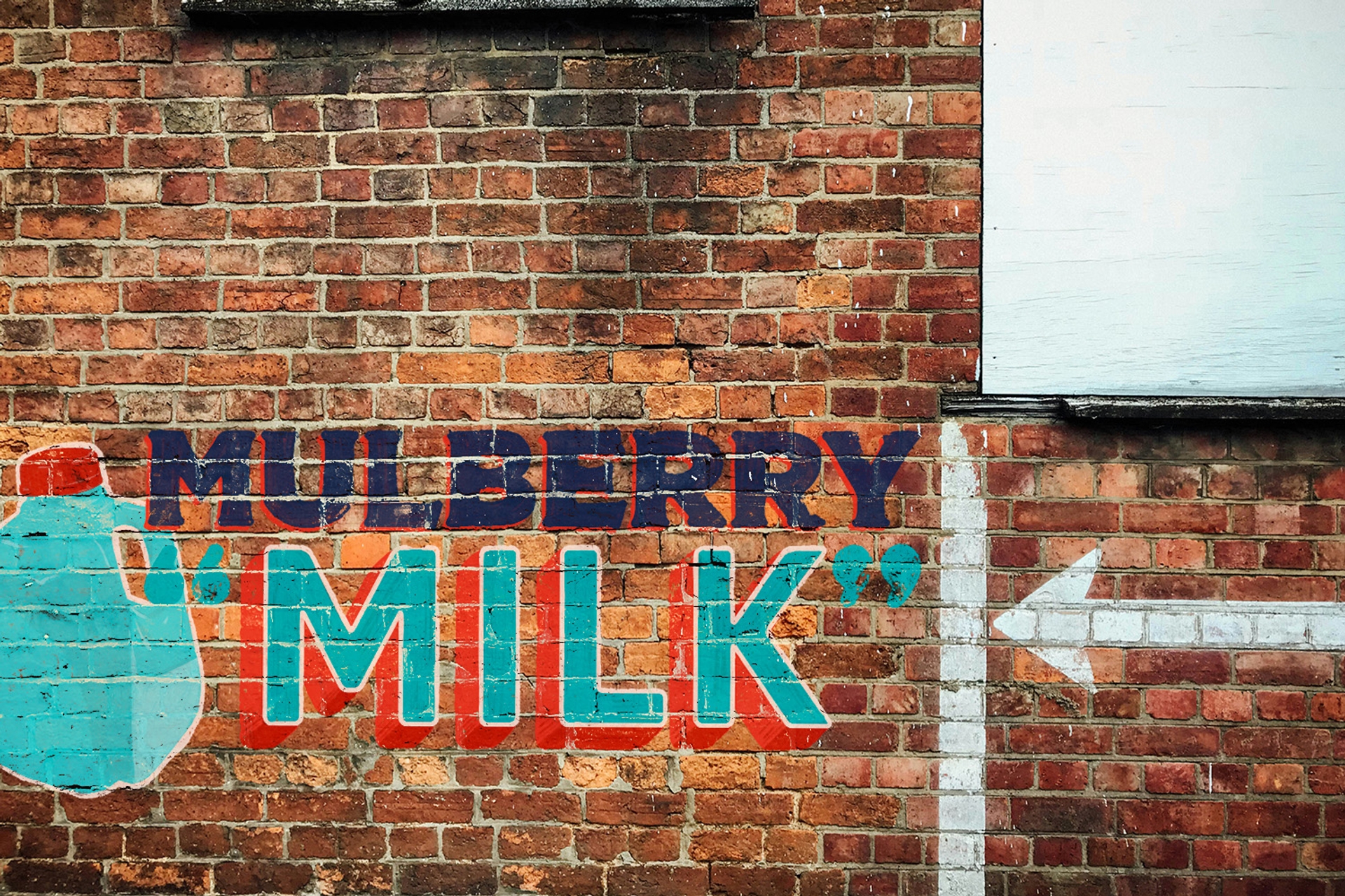 Ghost sign on brick reading Mulberry "Milk" with an arrow