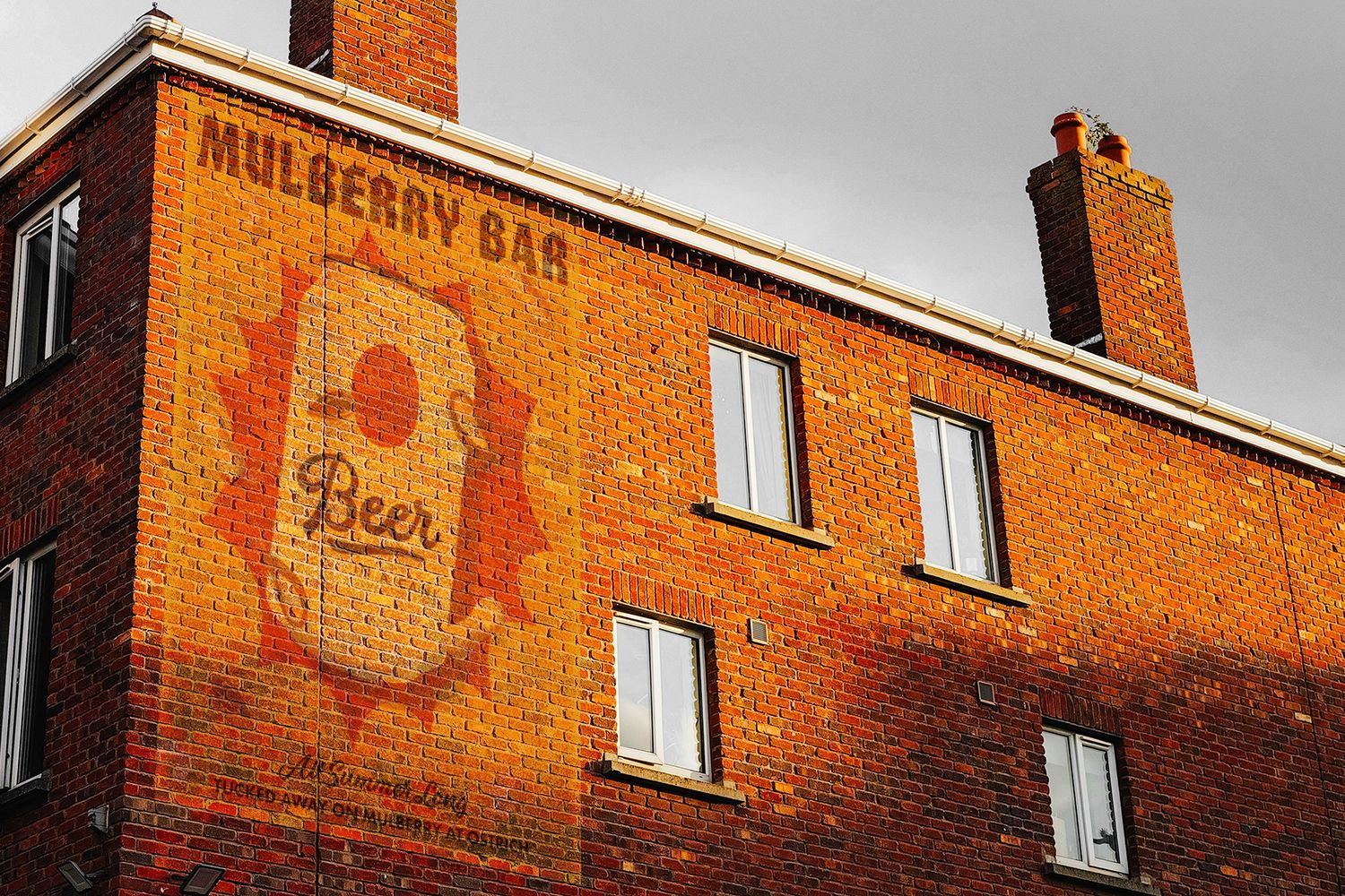 Ghost image of an old sign on a brick wall that says Mulberry Bar
